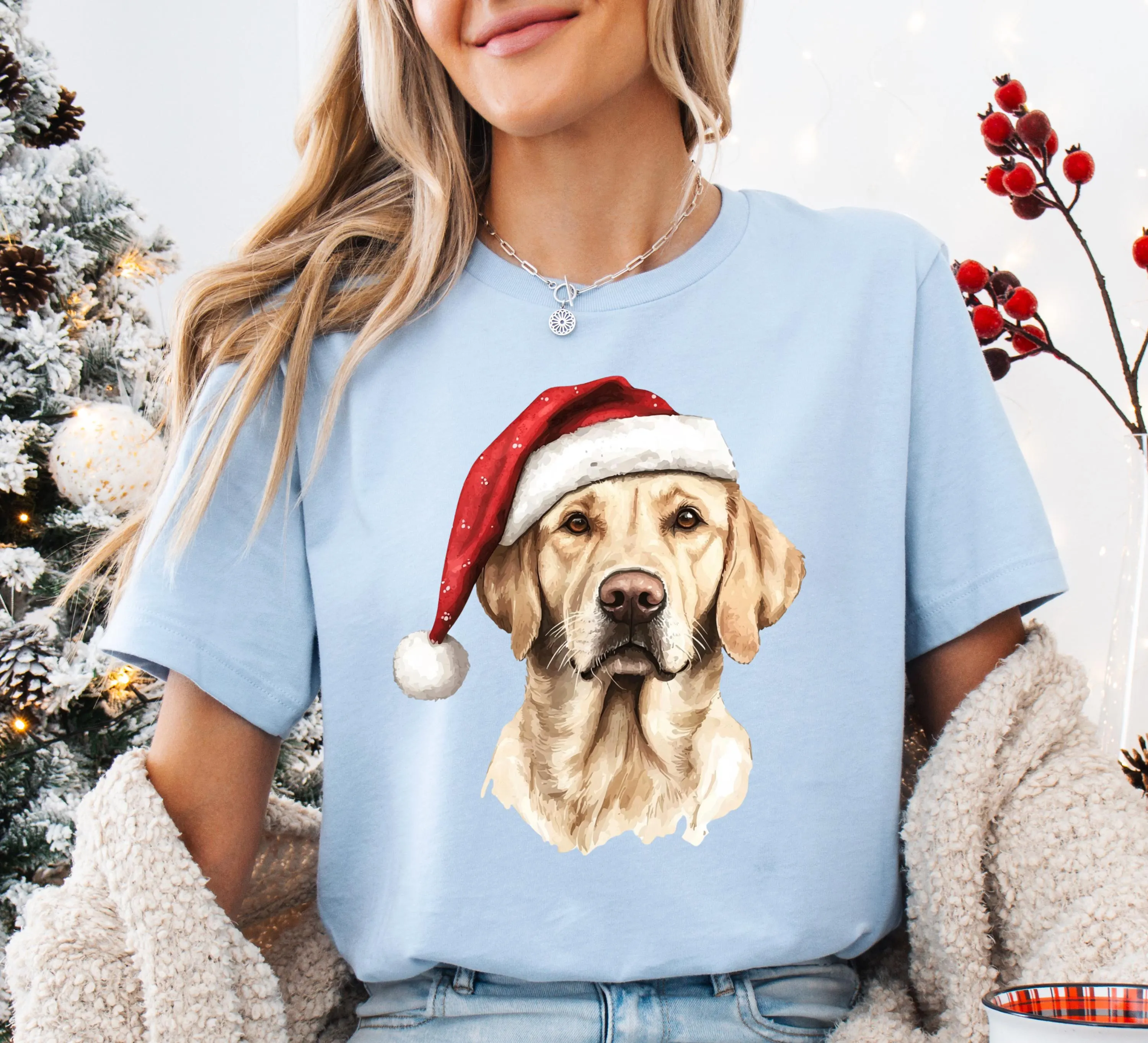 A woman wearing a light blue t-shirt with a picture of a dog wearing a Santa hat.