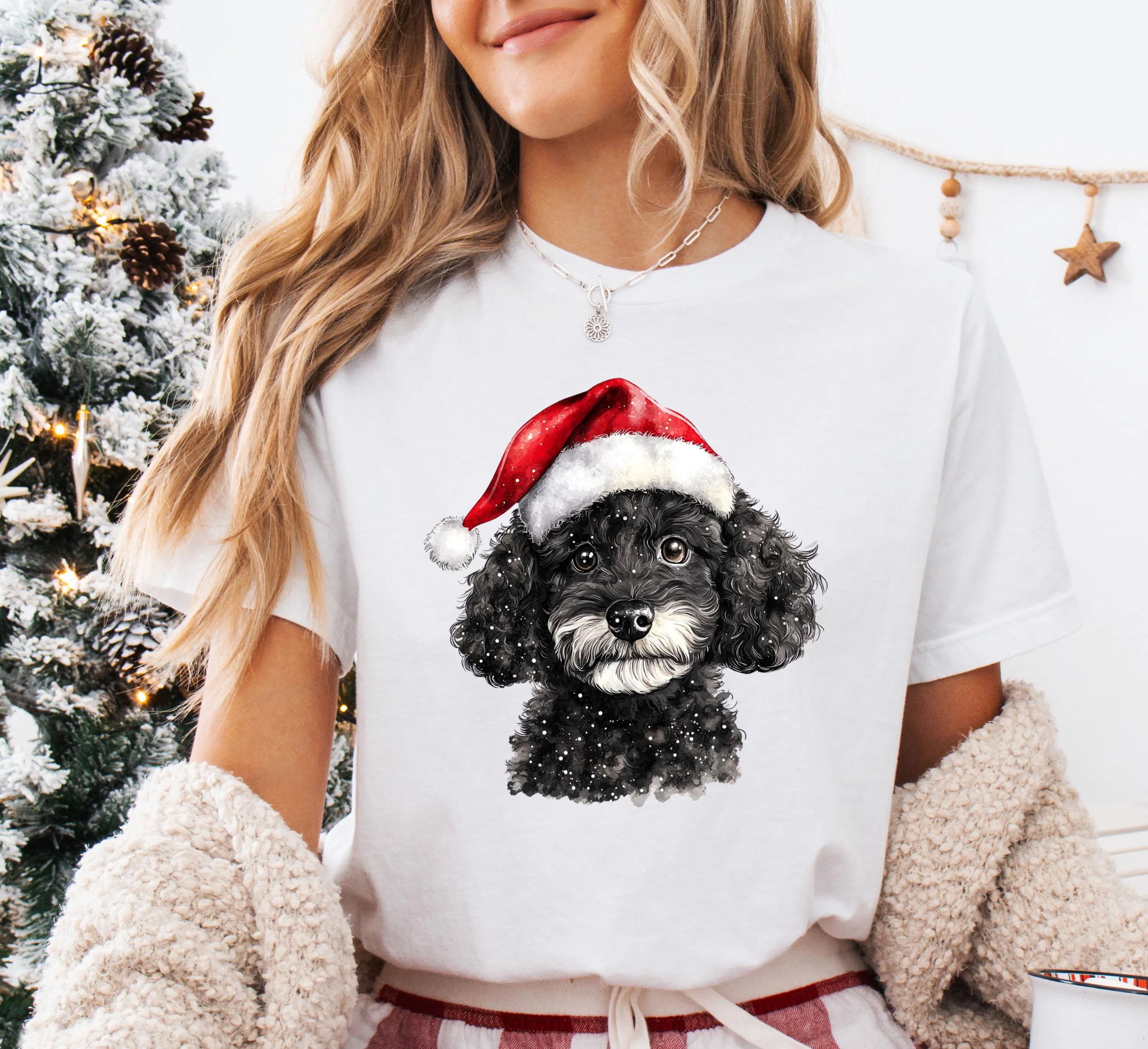 A woman wearing a white t-shirt with a black dog wearing a red Santa hat.