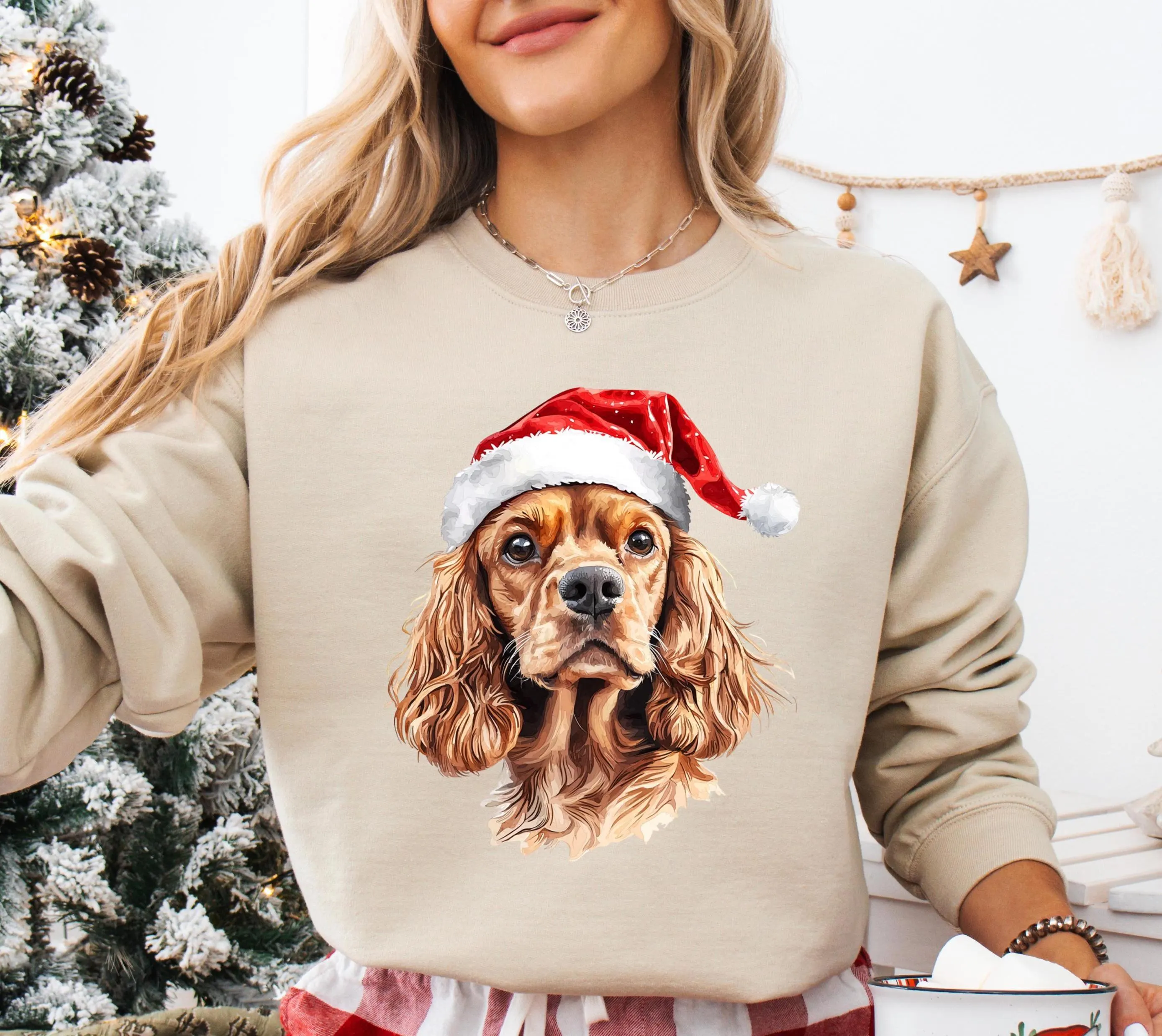 A woman wearing a beige sweater with a Christmas-themed dog wearing a Santa hat.
