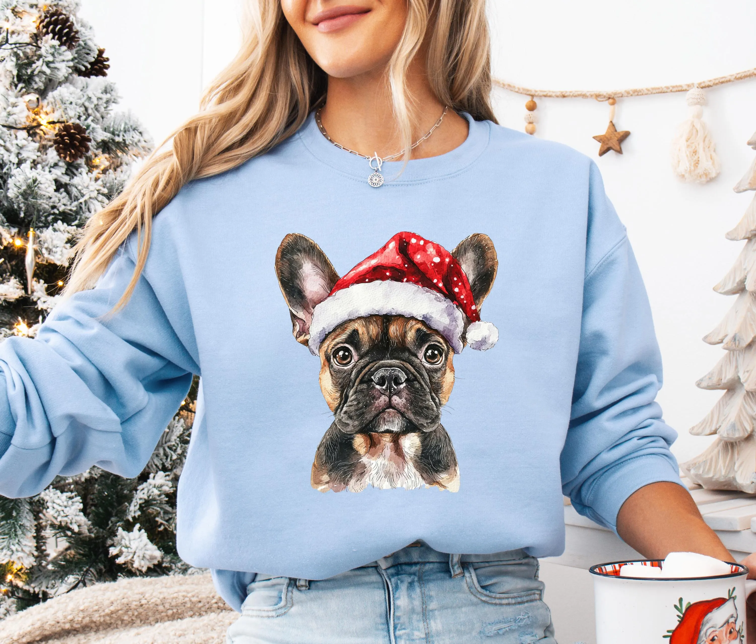 A woman wearing a blue sweatshirt with a picture of a dog wearing a Santa hat.