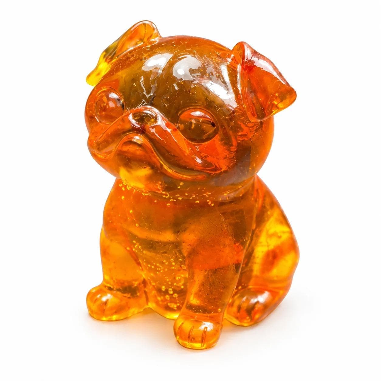 Golden Baltic amber seated Pug figurine with a flat wrinkled muzzle and folded ears isolated on a white background.