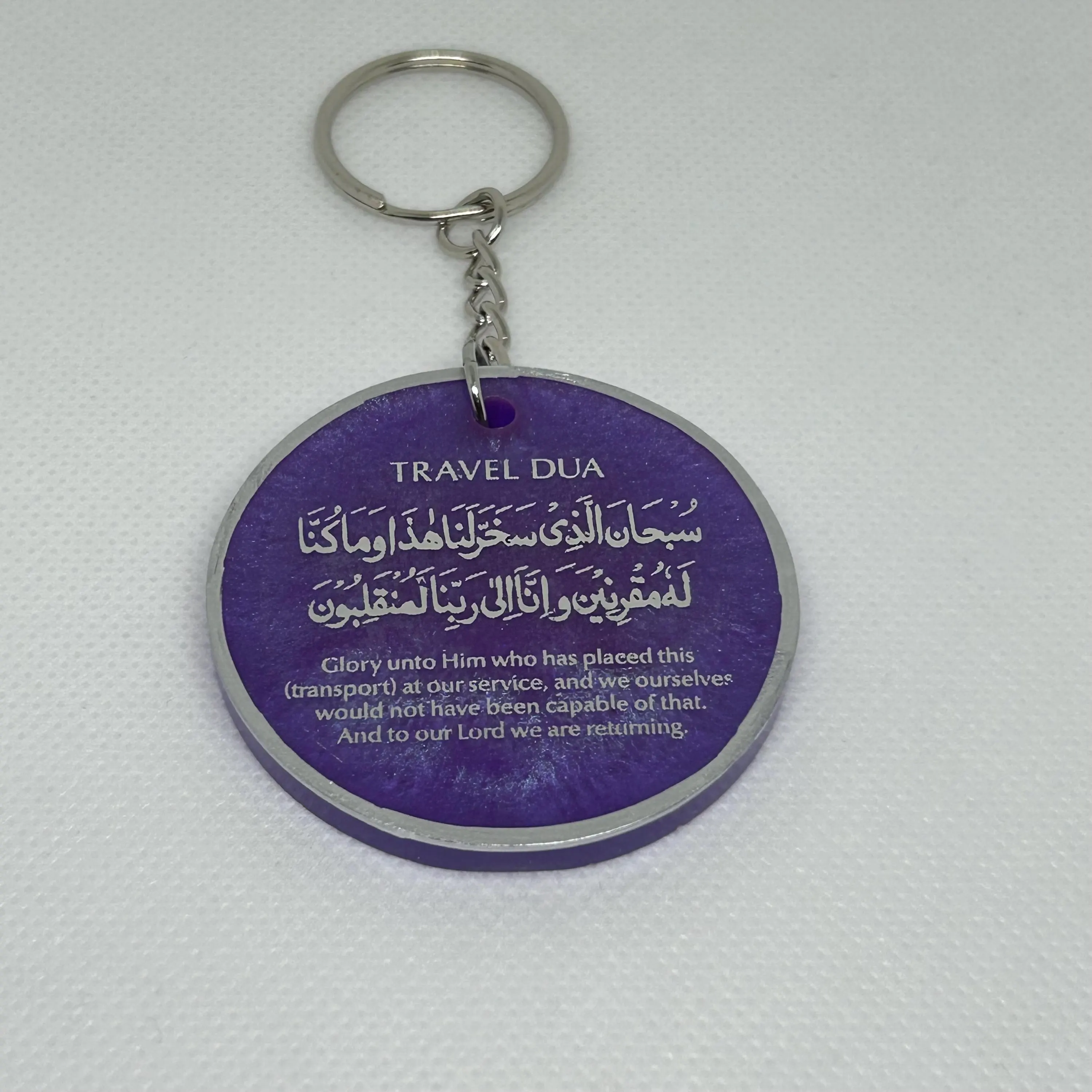 Round 5cm resin keyring in iridescent purple with the Arabic travel dua with English translation in silver text with a silver edge