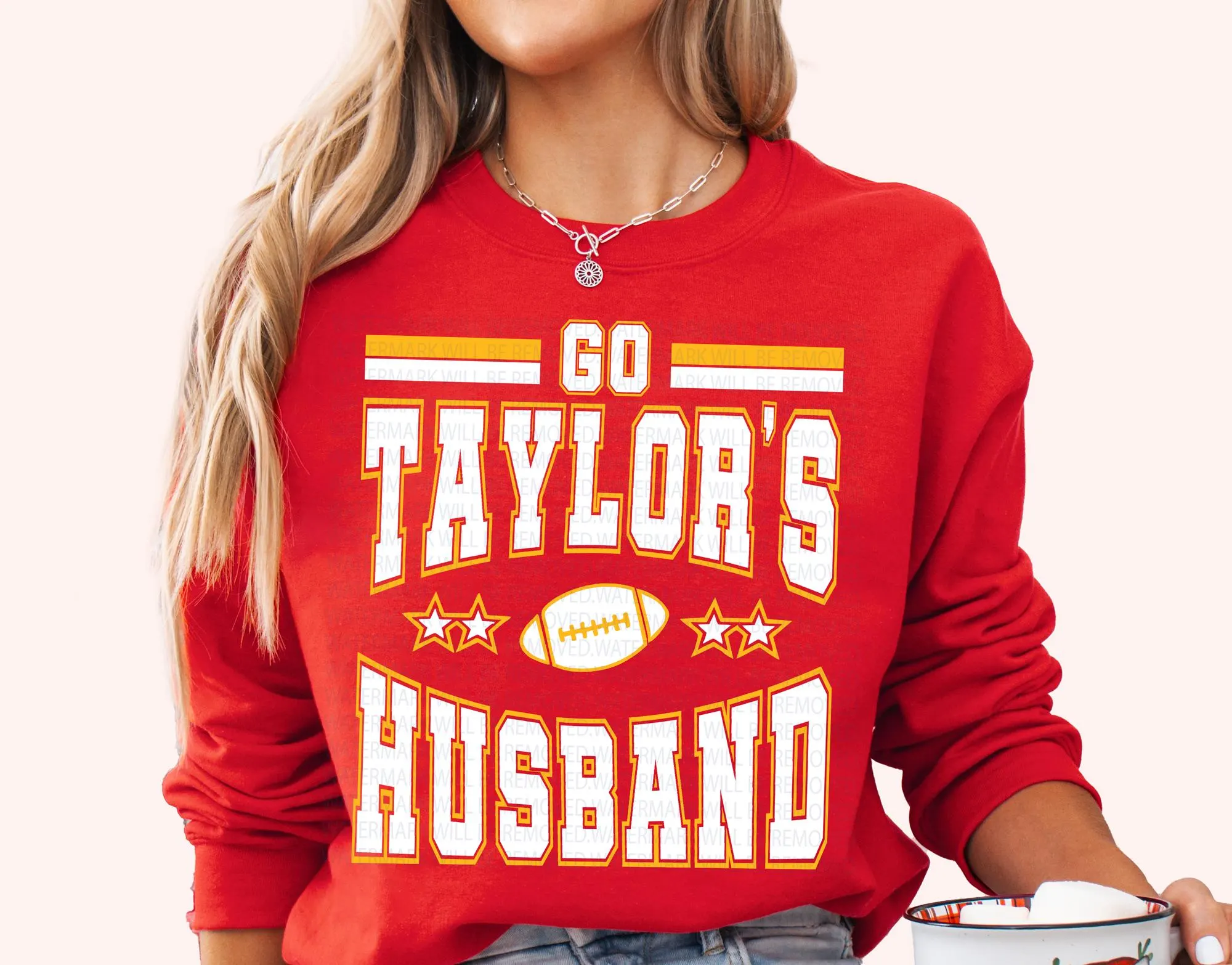 A woman wearing a red sweatshirt with the text "GO TAYLOR'S HUSBAND" printed on it.