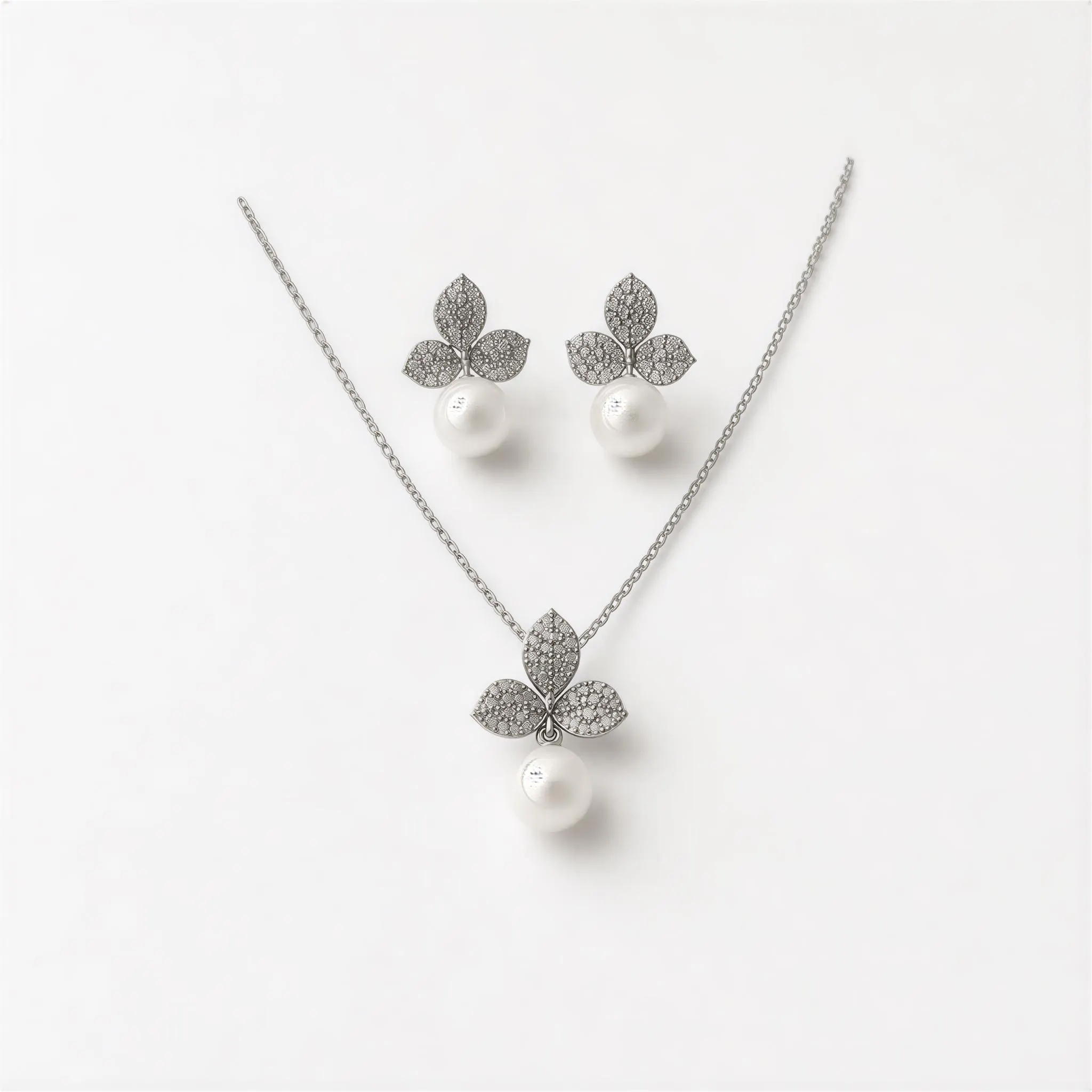 A necklace and earrings set made of silver and white materials, featuring a leaf-shaped pendant and pearl-like charms.