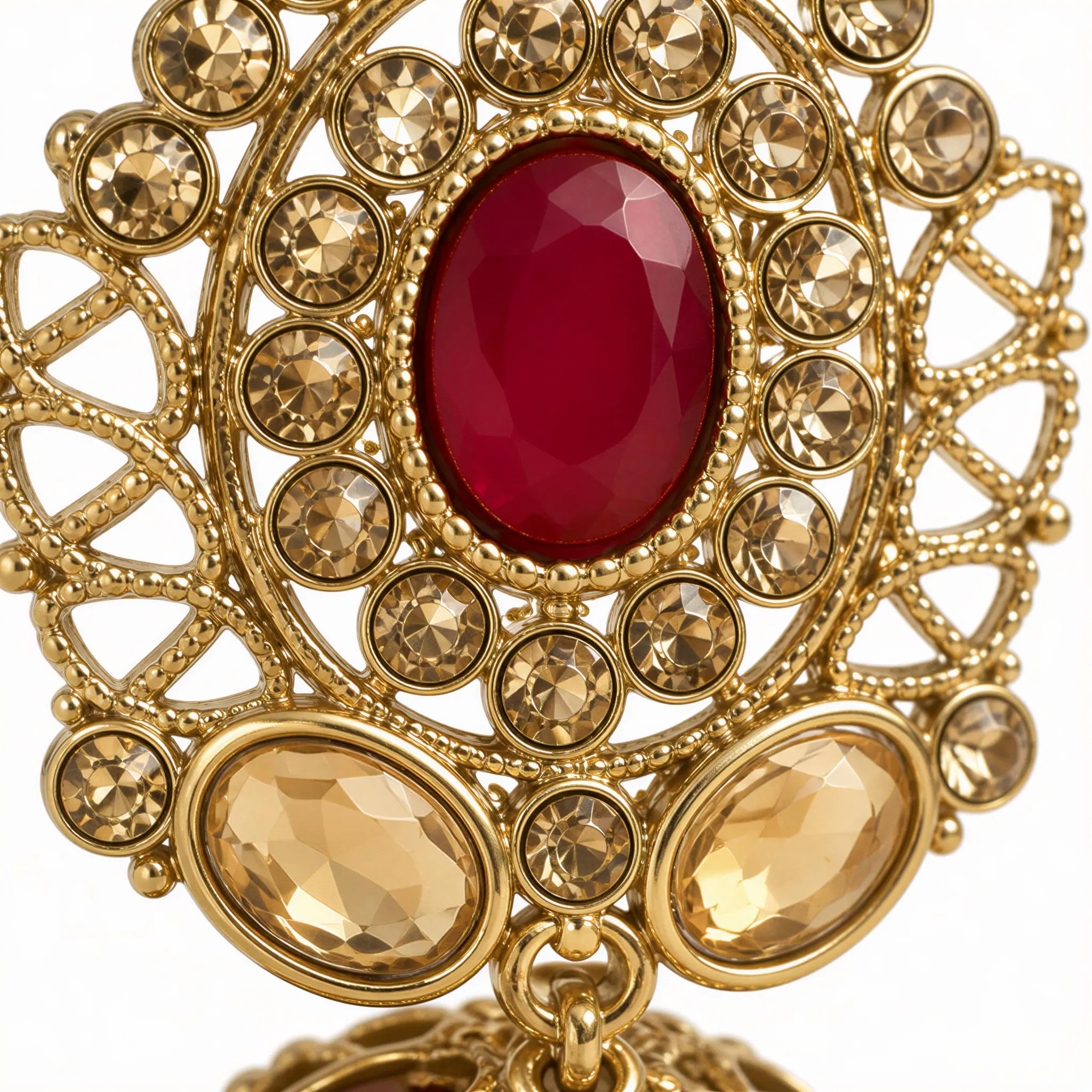 a close-up view of a decorative gold earring with a large red gemstone at its center. The earring is adorned with numerous small gold-colored gemstones, creating a visually striking and intricate design.