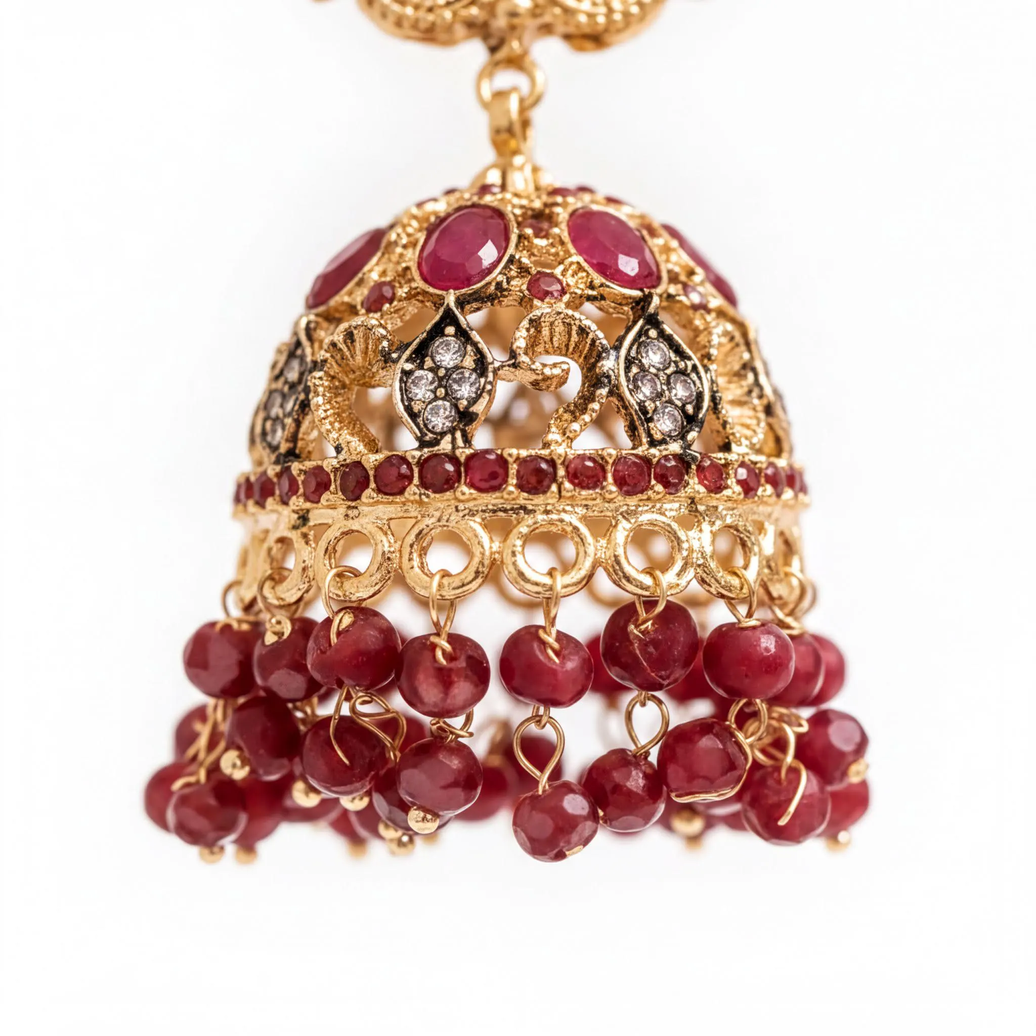 A close-up view of an ornate gold and red beaded earring with dangling red gemstones.