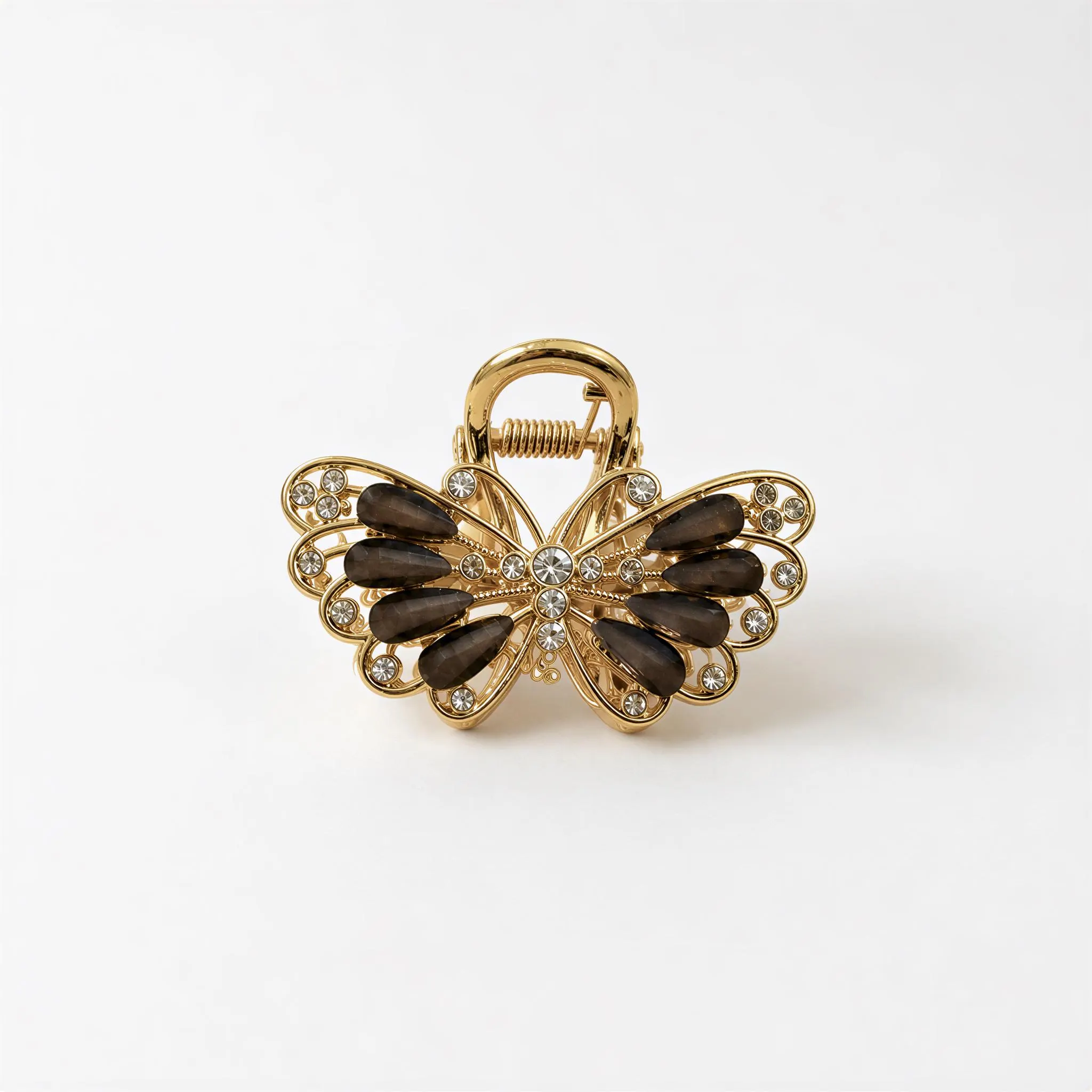 A gold-colored hair clip with a butterfly design, adorned with black gemstones.