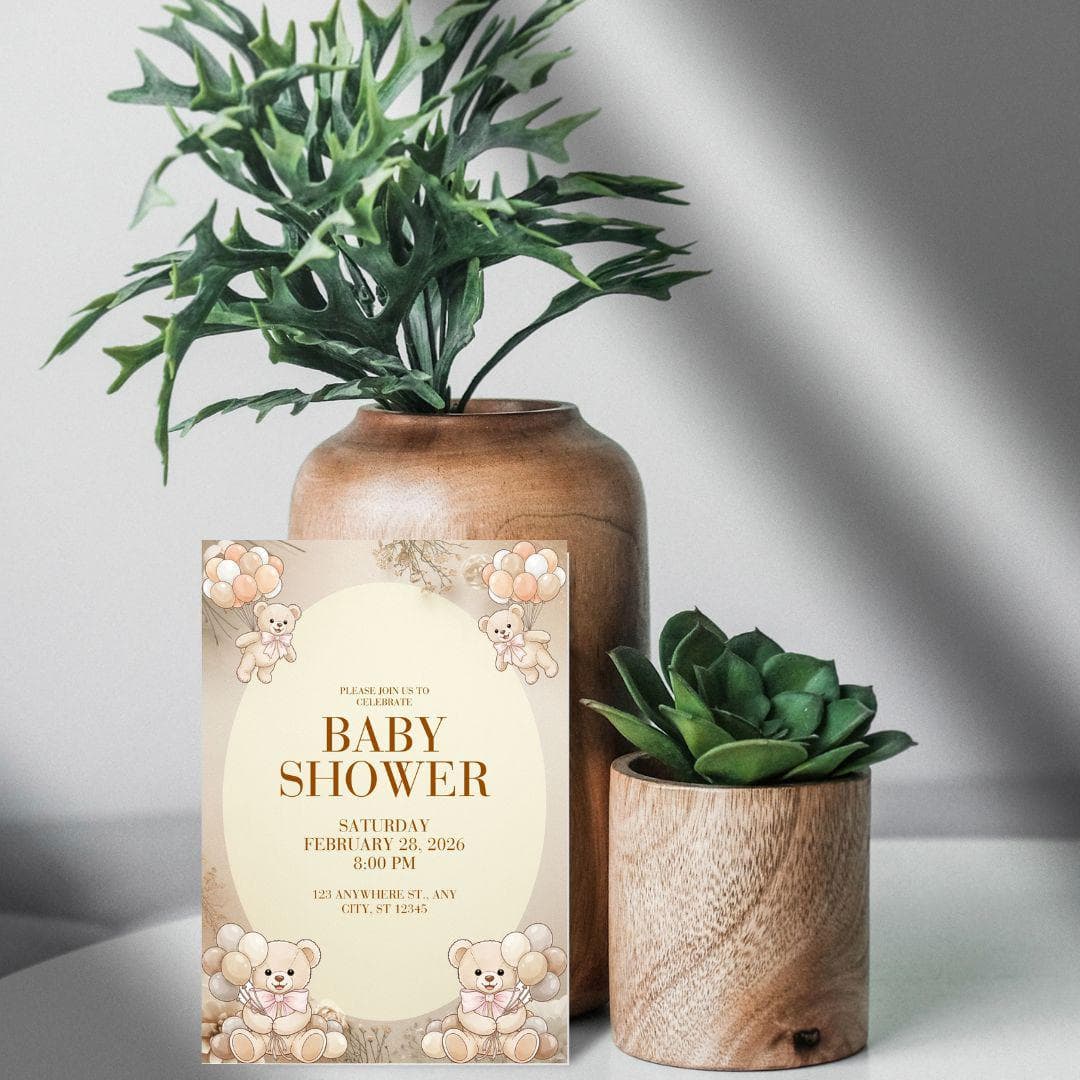 May include: Baby shower invitation featuring teddy bear illustrations and balloons. The invitation has a beige background with brown text, including the date, time, and location. It's positioned in front of a wooden vase with greenery.