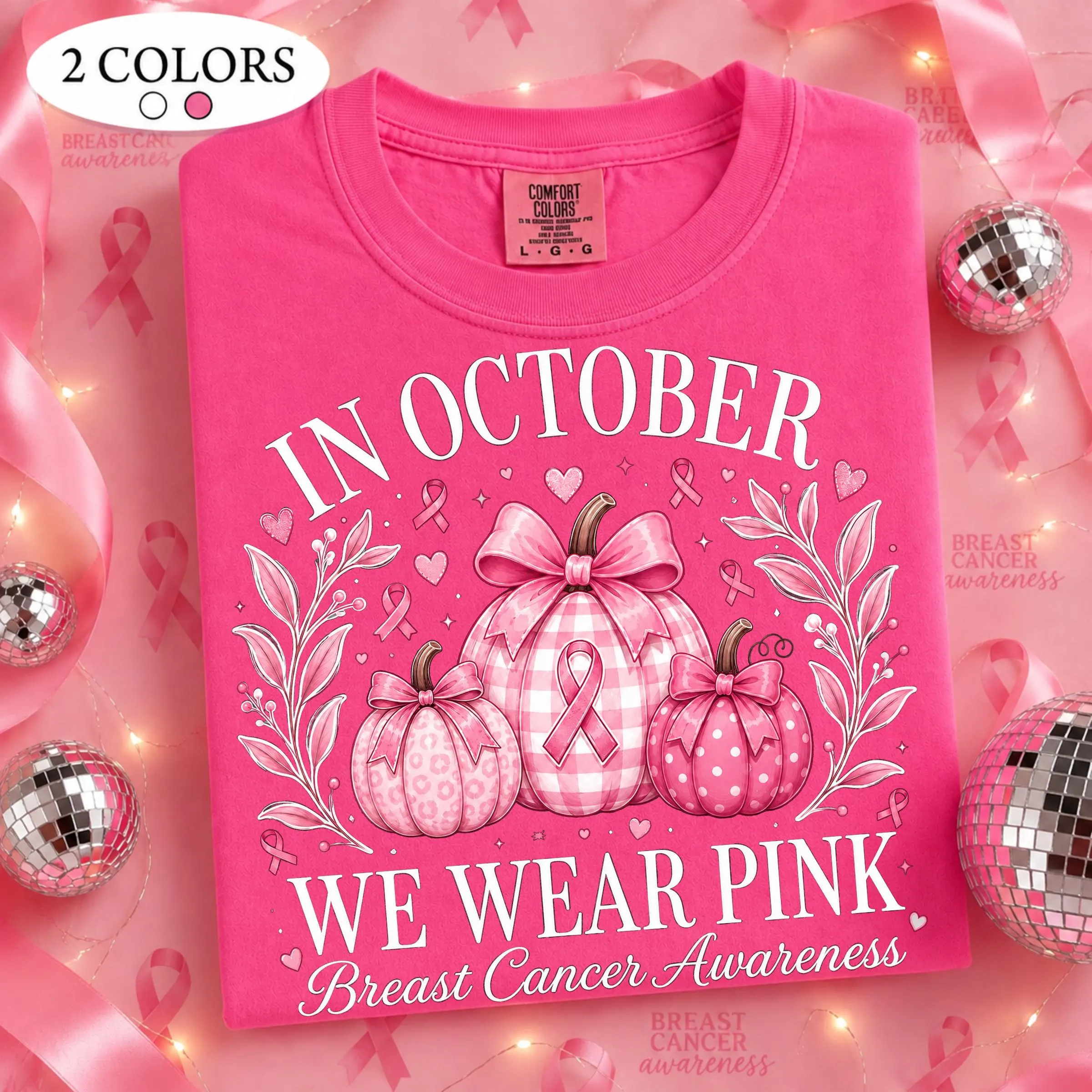 May include: A bright pink t-shirt featuring a graphic of three pumpkins with a breast cancer awareness ribbon. The text reads IN OCTOBER WE WEAR PINK Breast Cancer Awareness. The shirt has a Comfort Colors label indicating size large.