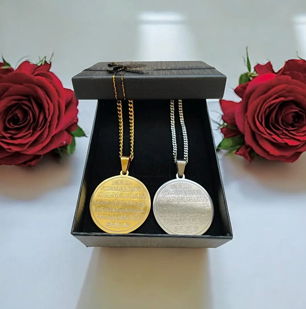 May include: Two circular pendant necklaces, one gold-toned and one silver-toned, presented in a black gift box. Each pendant features an intricate design. The necklaces are displayed with two red roses.