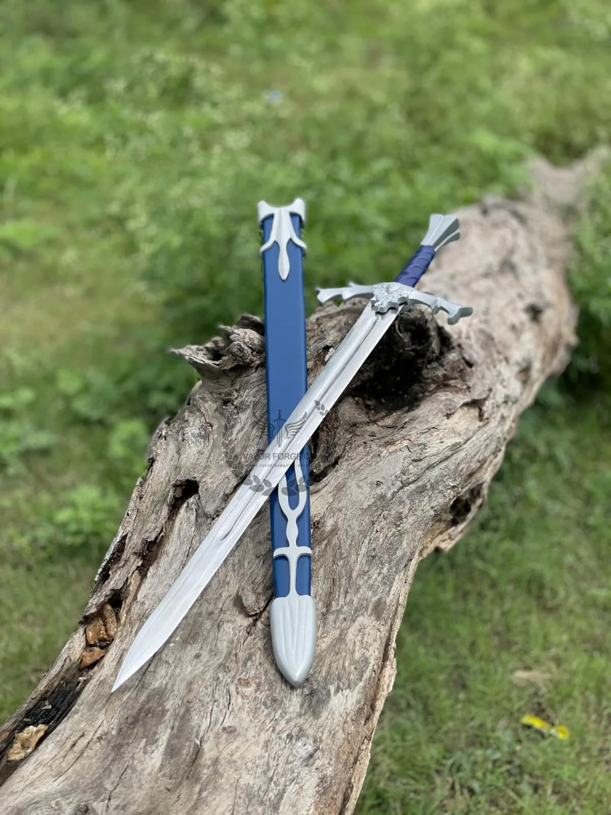 Decorative sword and blue scabbard placed together on a tree trunk, showing their matching design and contrasting colors.
