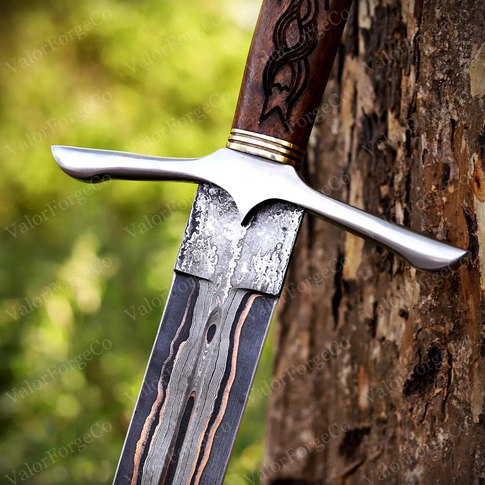 A sword with a patterned Damascus steel blade featuring dark and copper-coloured layers. The hilt has a polished silver-coloured crossguard, gold-coloured rings, and a dark brown wooden handle with an engraved knotwork design.