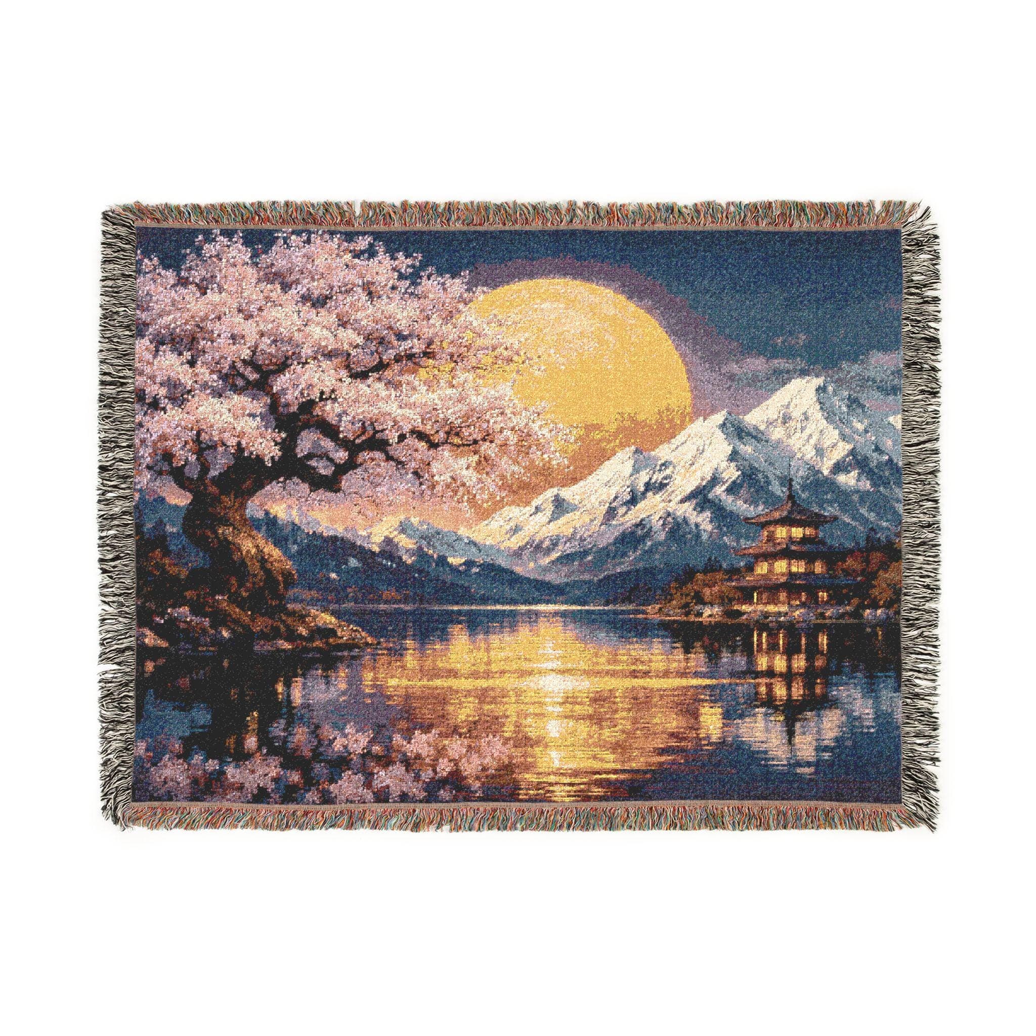 Woven tapestry blanket featuring a Japanese-inspired night landscape with pink cherry blossoms, a large golden moon, snowy mountains, and a pagoda beside a calm lake with shimmering reflections. Deep blue sky and warm light create a serene, zen mood. Fringed edges and detailed woven texture make it ideal as tapestry wall art, wall hanging, or cozy throw for bedroom, living room, reading nook, meditation space, or Asian-inspired home decor.