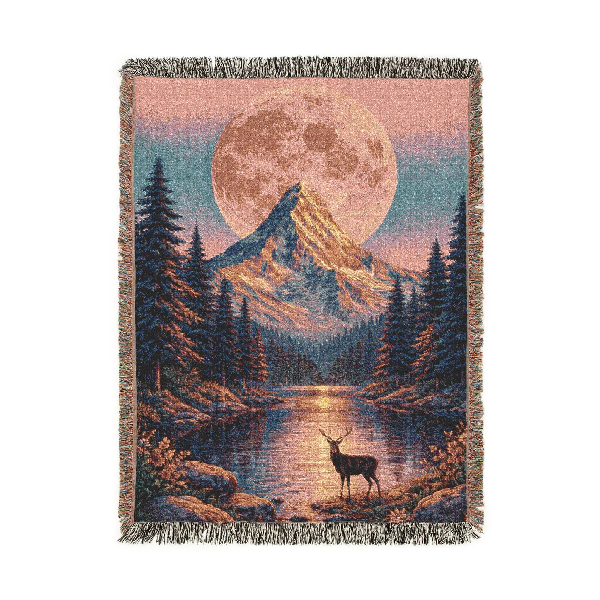 Woven tapestry wall hanging with a glowing full moon behind a snowcapped peak, pine forest, and lake reflection with a deer at the shore. Scenic mountain landscape in rustic cabin lodge style with sunset pink and deep blue tones, wildflower foreground, and fringe trim. Perfect as large tapestry wall art for bedroom, living room, dorm, studio, or cabin decor, and also cozy as a woven throw blanket for chilly nights. Gift for hikers, campers, mountain lovers, and wildlife fans.