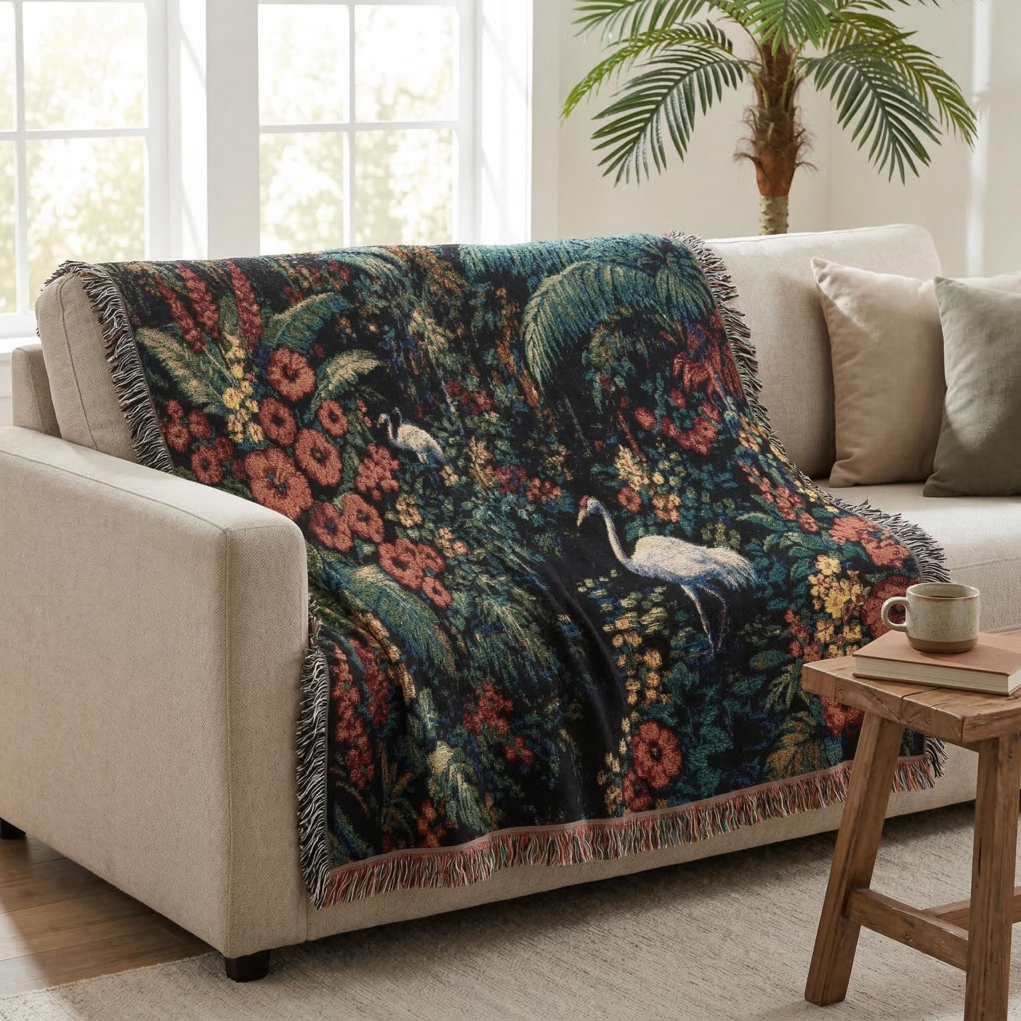 Woven tapestry wall hanging featuring white cranes in a lush tropical jungle filled with oversized flowers, palm leaves, dense foliage, and a dark moody botanical palette. Exotic garden wall decor in deep green, coral, gold, and ivory tones with rich woven texture and fringe. Ideal for maximalist bedroom decor, living room wall art, sunroom styling, or as a woven throw blanket. Perfect gift for bird lovers, plant lovers, tropical decor fans, and botanical home collectors.