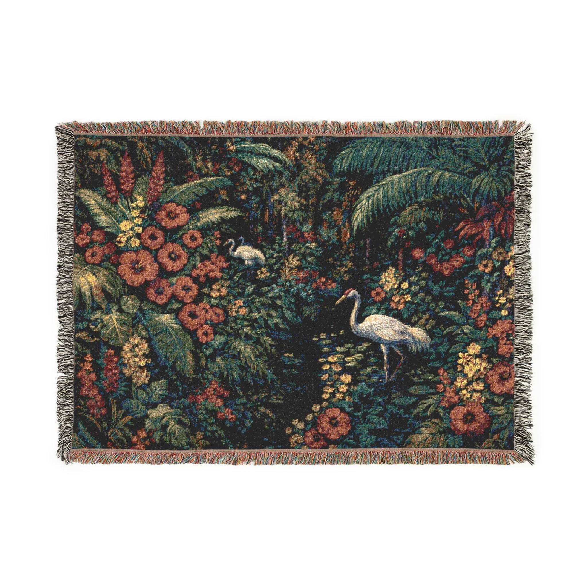 Woven tapestry wall hanging featuring white cranes in a lush tropical jungle filled with oversized flowers, palm leaves, dense foliage, and a dark moody botanical palette. Exotic garden wall decor in deep green, coral, gold, and ivory tones with rich woven texture and fringe. Ideal for maximalist bedroom decor, living room wall art, sunroom styling, or as a woven throw blanket. Perfect gift for bird lovers, plant lovers, tropical decor fans, and botanical home collectors.