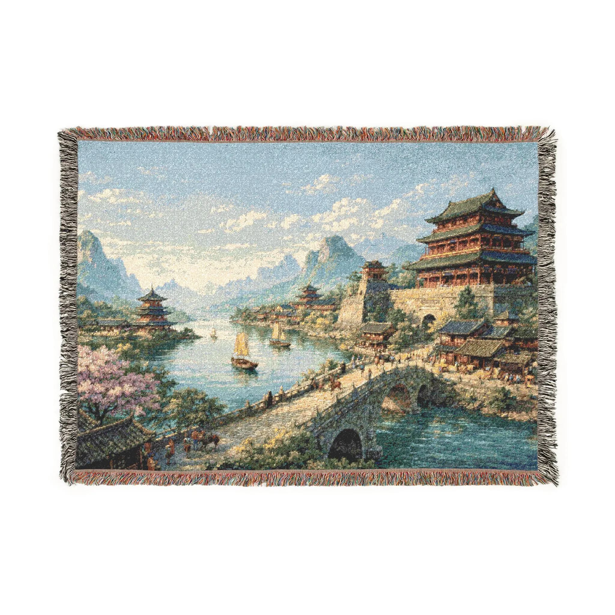 Woven tapestry wall hanging featuring a serene Chinese river village with Asian palace rooftops, pagoda towers, arched stone bridge, small sailboats, mountain landscape, blooming trees, and reflective blue water under a bright sky. Scenic Asian wall art with traditional architecture, lake scenery, and vintage woven texture, ideal as a large wall tapestry, woven throw blanket, Chinese home decor, living room accent, bedroom wall decor, travel inspired decor, and gift for landscape art collectors.