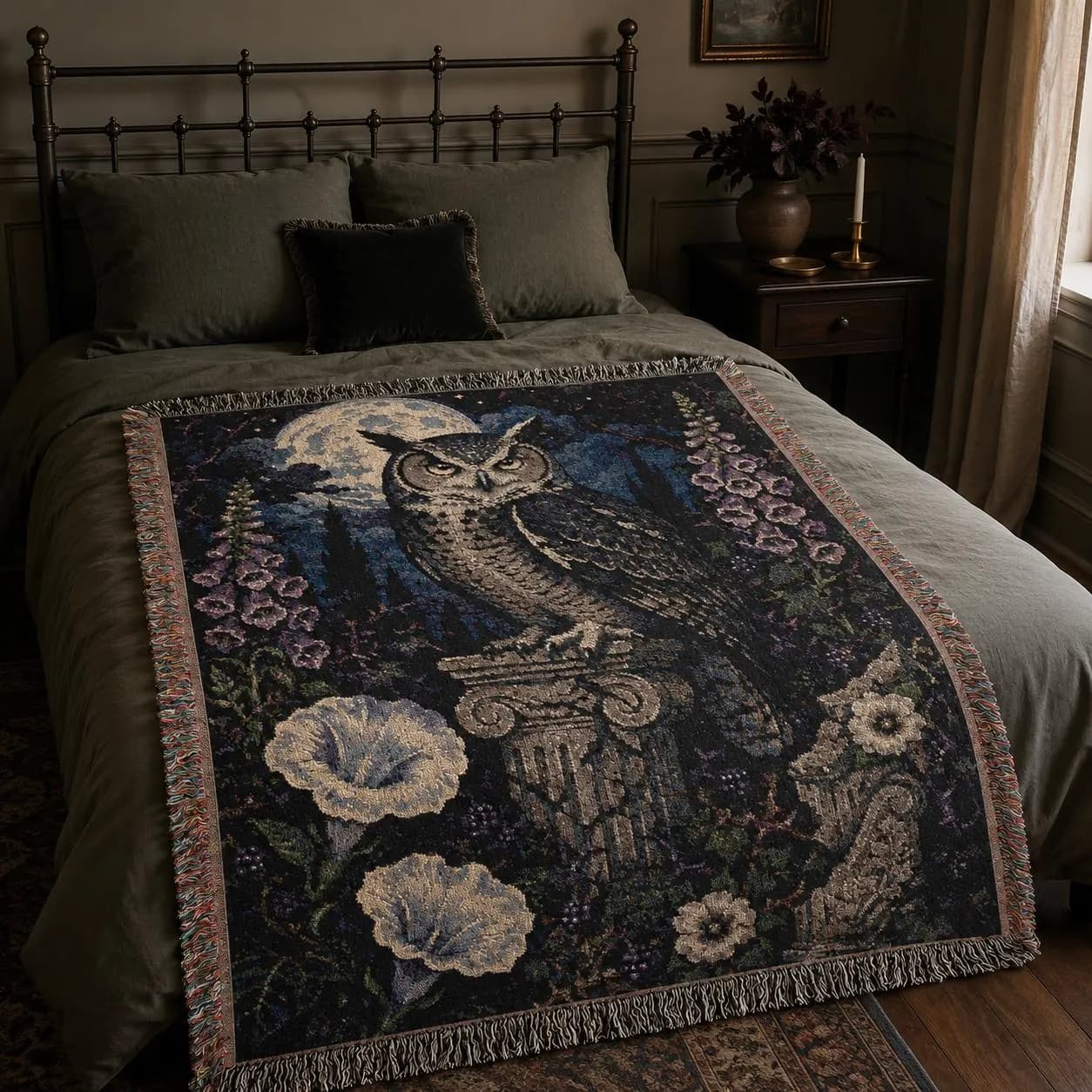 Vertical woven blanket wall hanging with a large owl on a stone column beneath a full moon, surrounded by purple foxglove-like flowers, white moonflowers, dark foliage, starry night sky, and fringed textile edges.