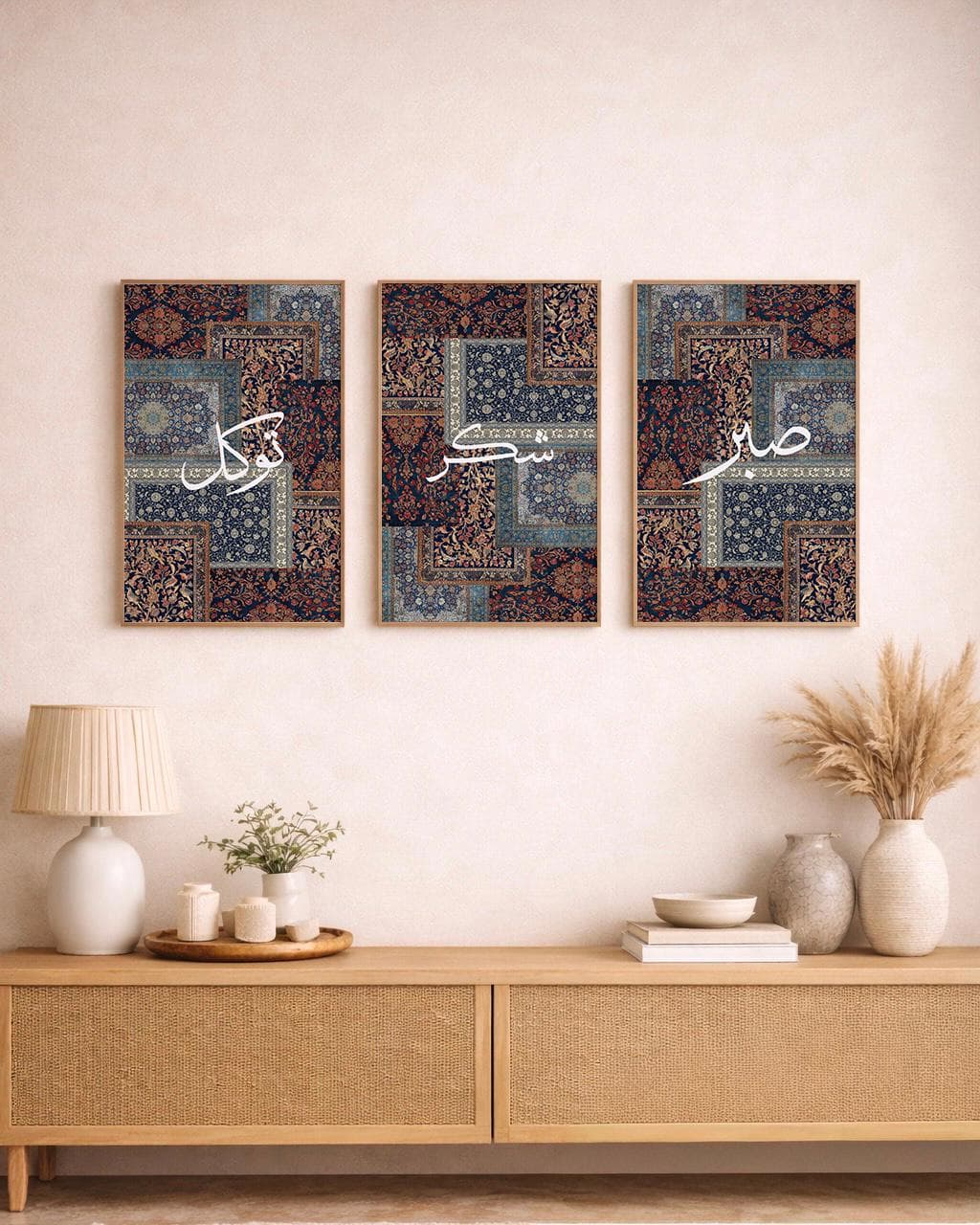 May include: Three framed wall art pieces with a patchwork design in shades of blue, brown, and beige. Each piece features white Arabic calligraphy. The artwork is displayed above a wooden cabinet with a lamp and decorative items.