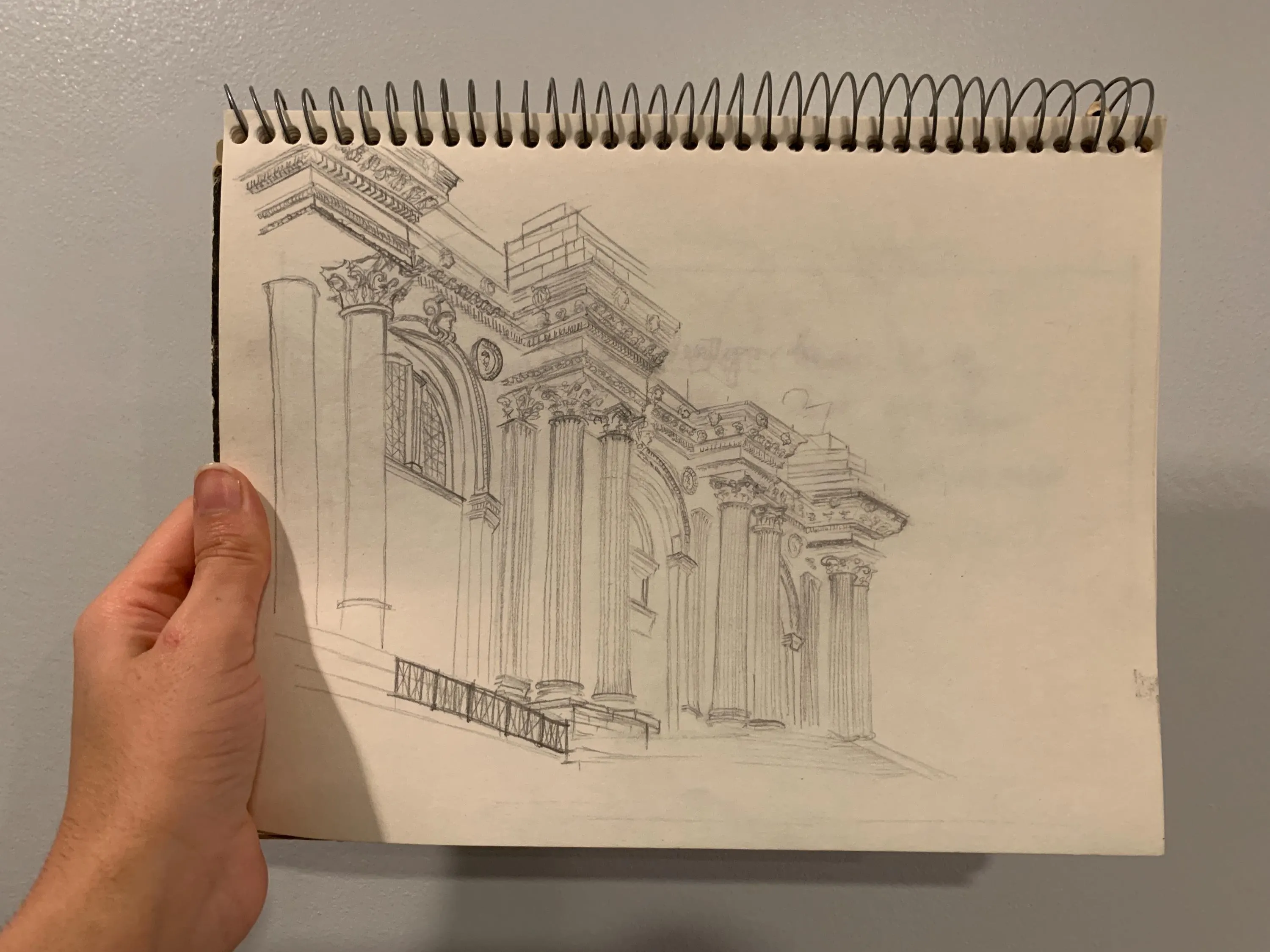 A pencil sketch of a classical building facade with columns, arches, and architectural details.