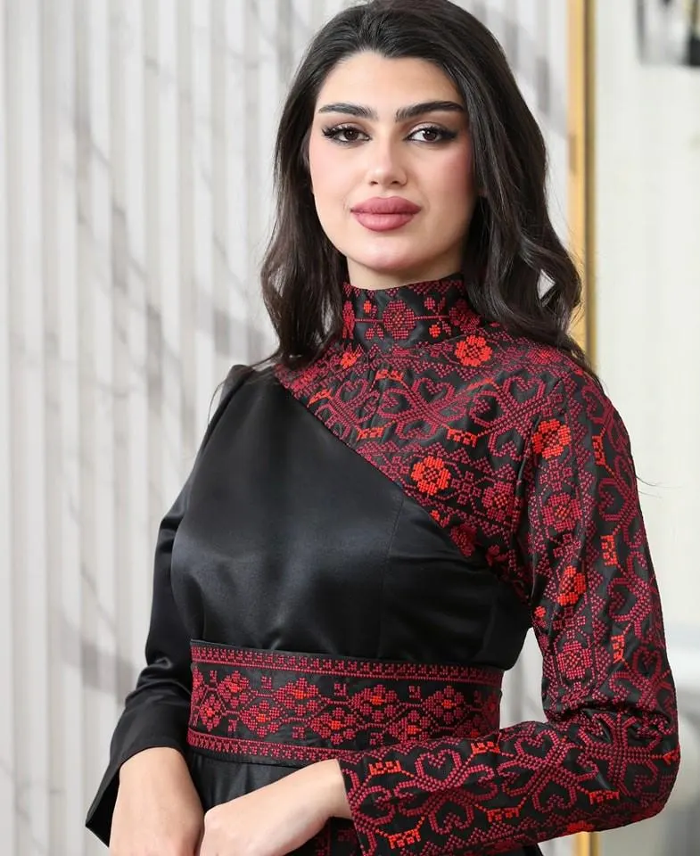 May include: A black dress with red embroidered detailing. The dress features a high neckline and long sleeves. The red embroidery is concentrated on the neckline, sleeves, and waist, creating a striking contrast against the black fabric.