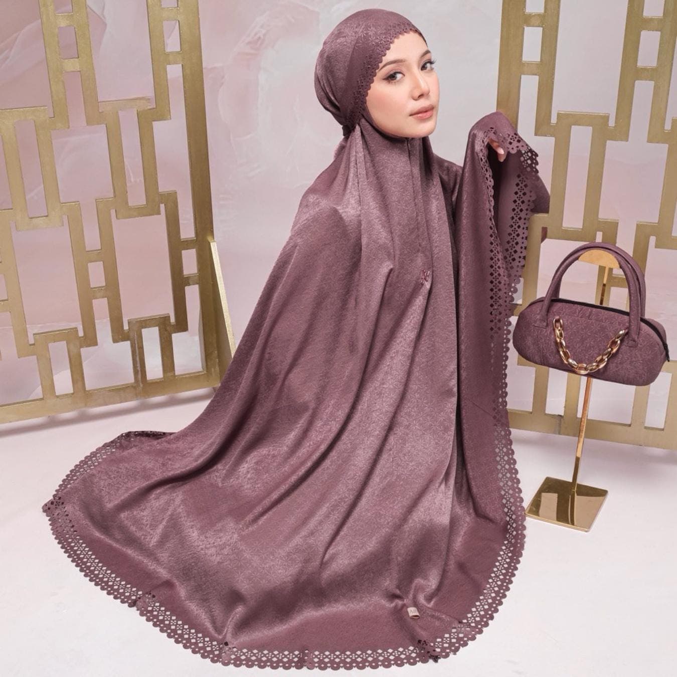 May include: A mauve prayer garment with a matching head covering and a decorative edge. A small, matching handbag with a gold chain handle sits on a gold stand. The fabric has a subtle sheen.