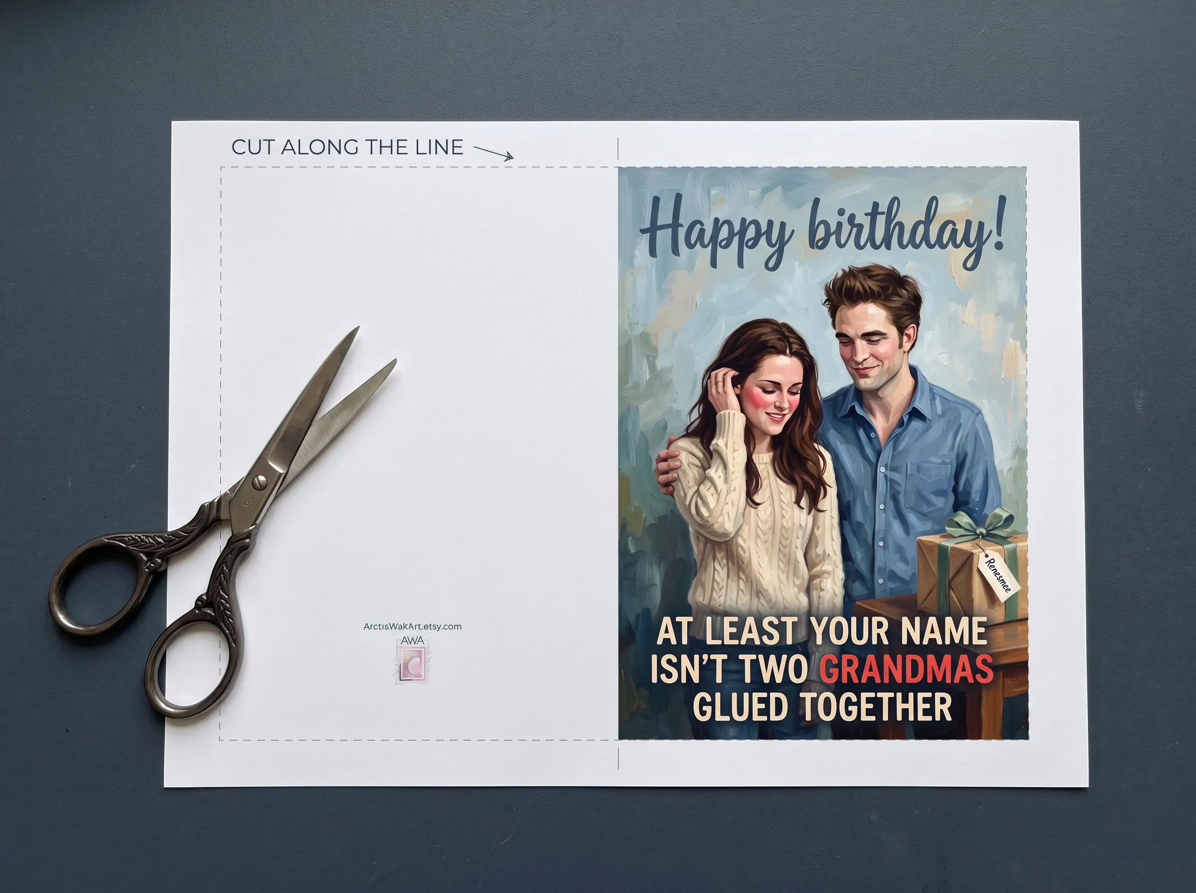 Postcard digital layout of the Twilight birthday card before cutting: a dashed cut line around the card, a blank back panel with a small ArcticWallArt mark, and a front with Bella Swan and Edward Cullen beside a gift tagged Renesmee, with the text Happy birthday! At least your name isn't two grandmas glued together. Print, cut and fold into a 5 x 7 inch funny birthday card.