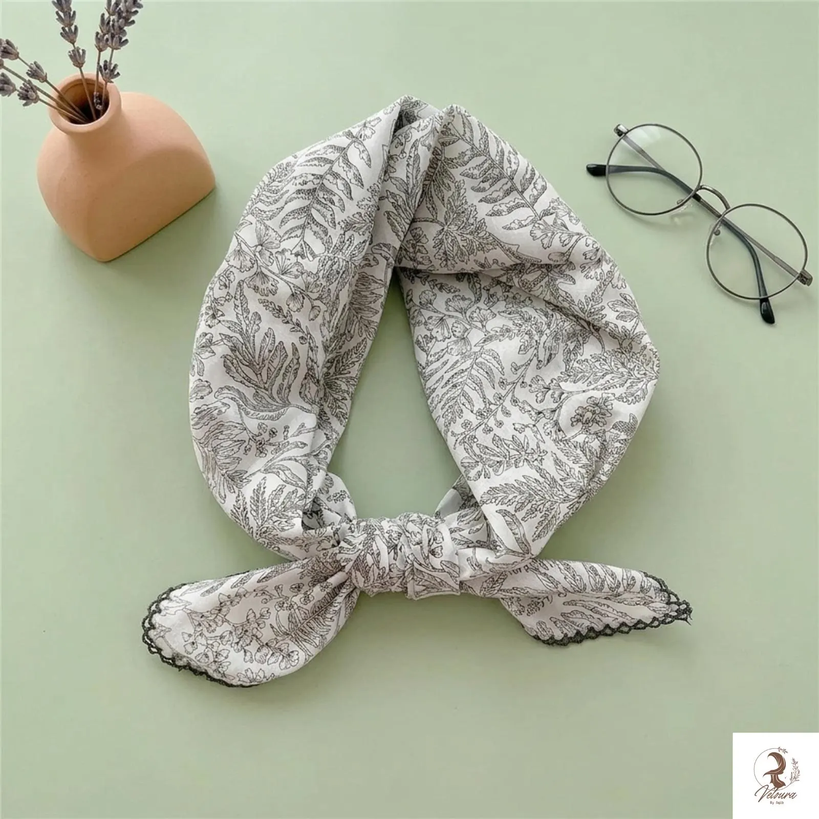 Soft cotton scarf tied around a handbag handle as a decorative accessory