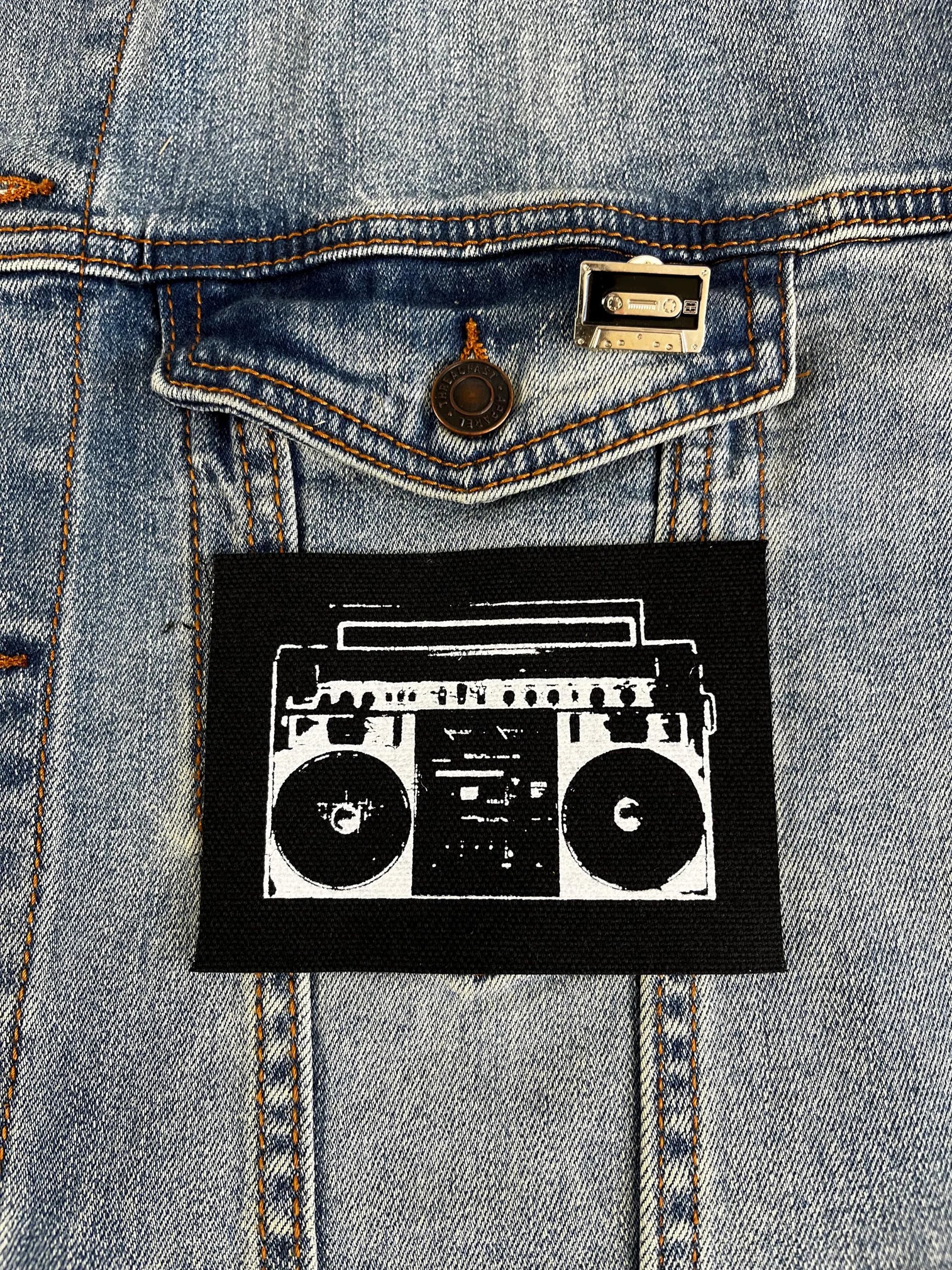 Punk patch with a hand-drawn boombox design, screen printed in black and white on fabric, laid flat for clear detail.