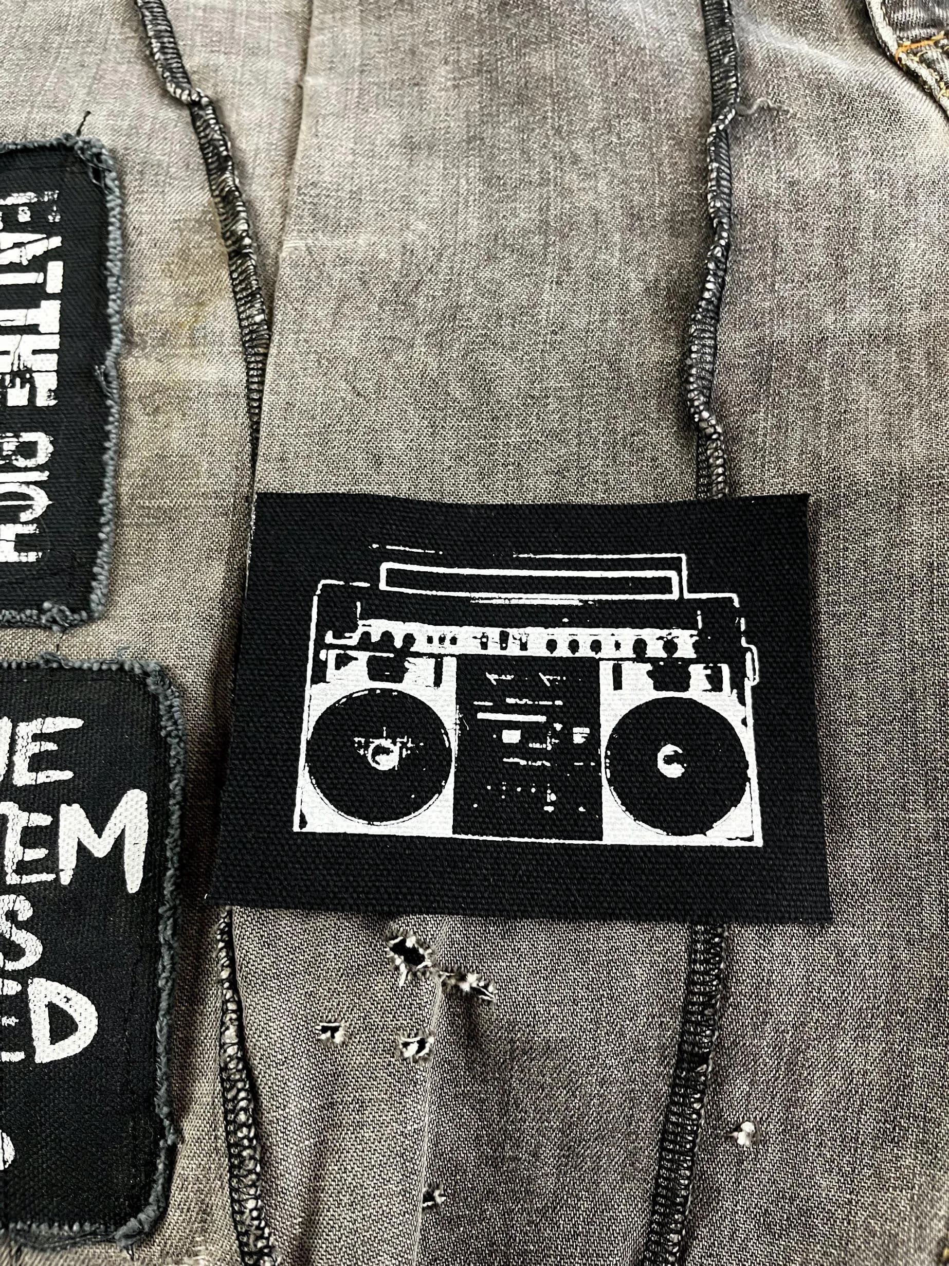 Close-up of boombox design on punk patch, showing screen print detail and fabric texture.