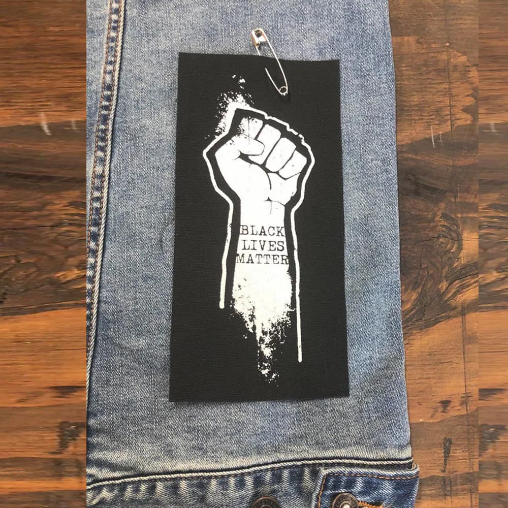 May include: Black and white iron-on patch with a raised fist and the text "Black Lives Matter".