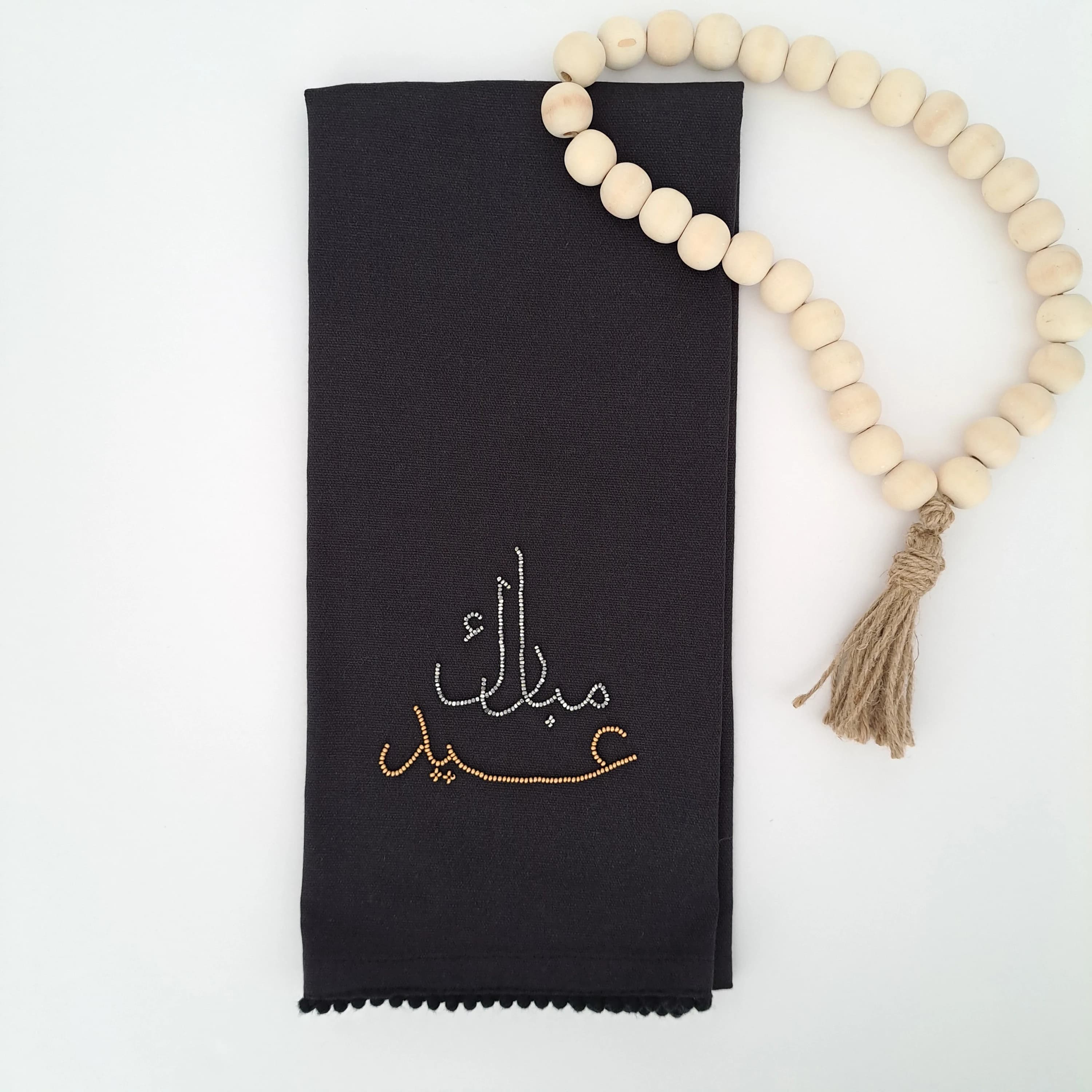 black tea towel with bead embroidery. eid mubarak in arabic calligraphy in silver and gold