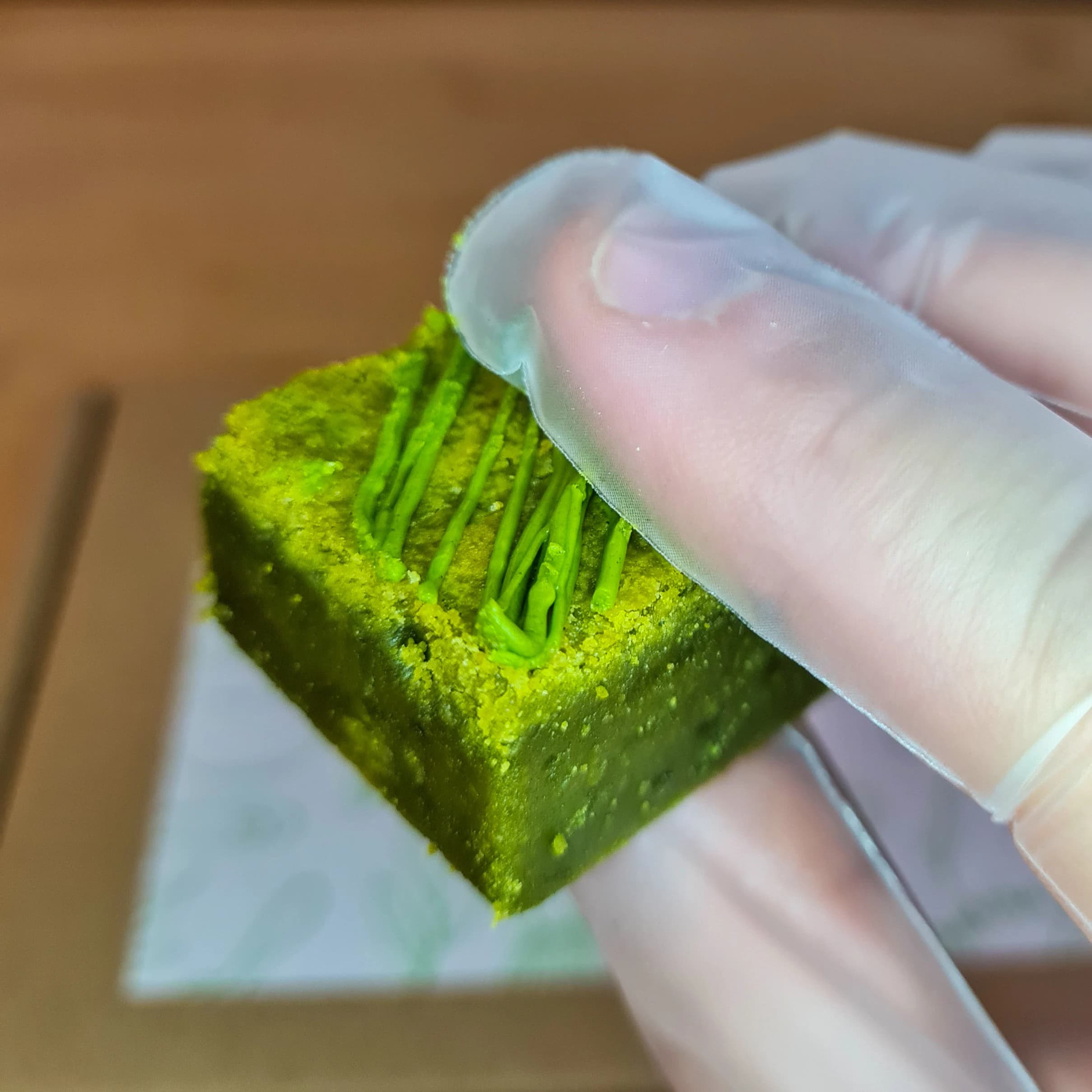 Close up of a matcha blondie bite, made with Culinary Grade Organic Japanese Matcha, green in colour, in a gift box containing 18 bites