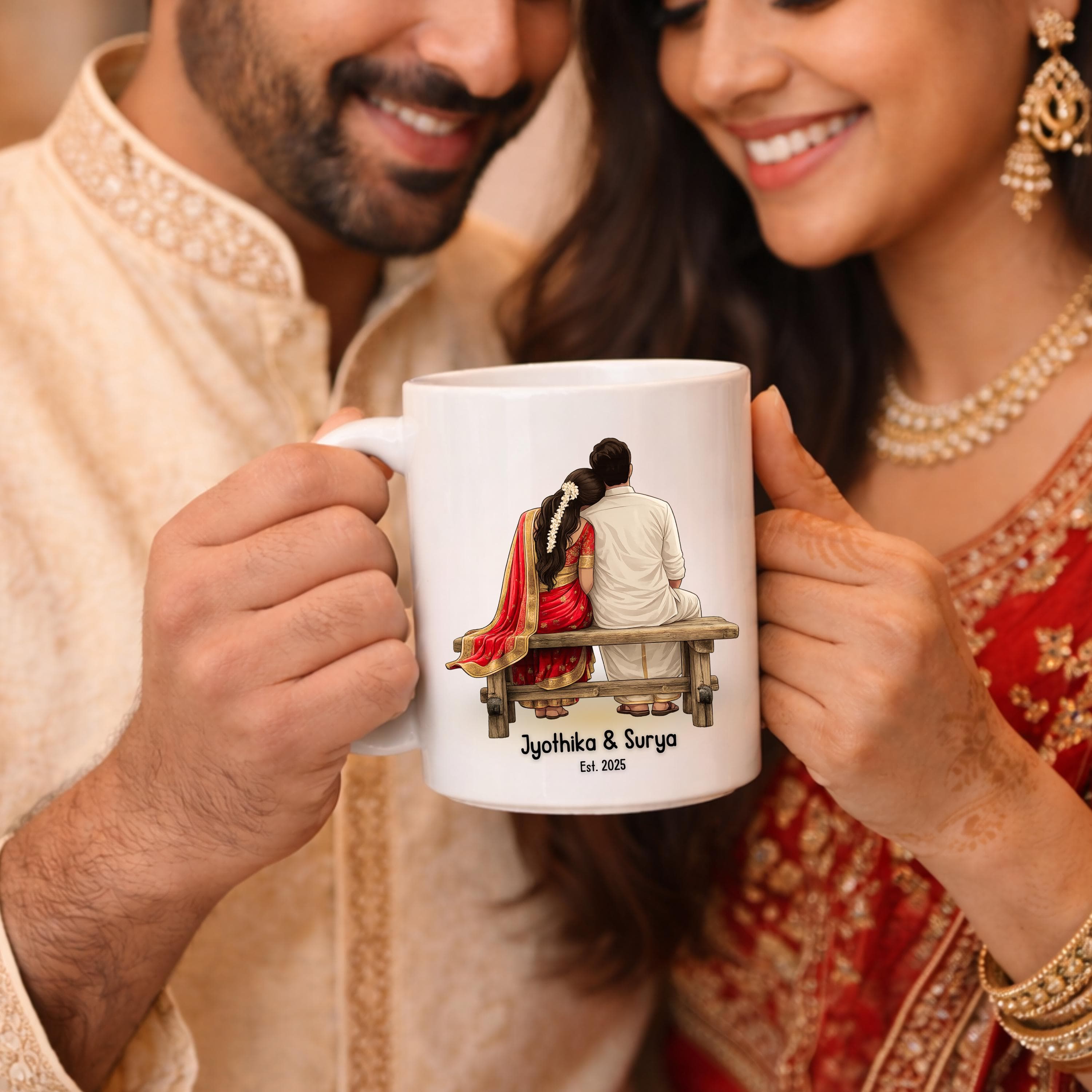 May include: White ceramic mug featuring an illustration of a couple sitting on a bench, with the text "Jyothika & Surya Est. 2025". The couple is depicted in traditional Indian attire. The mug has a white handle.