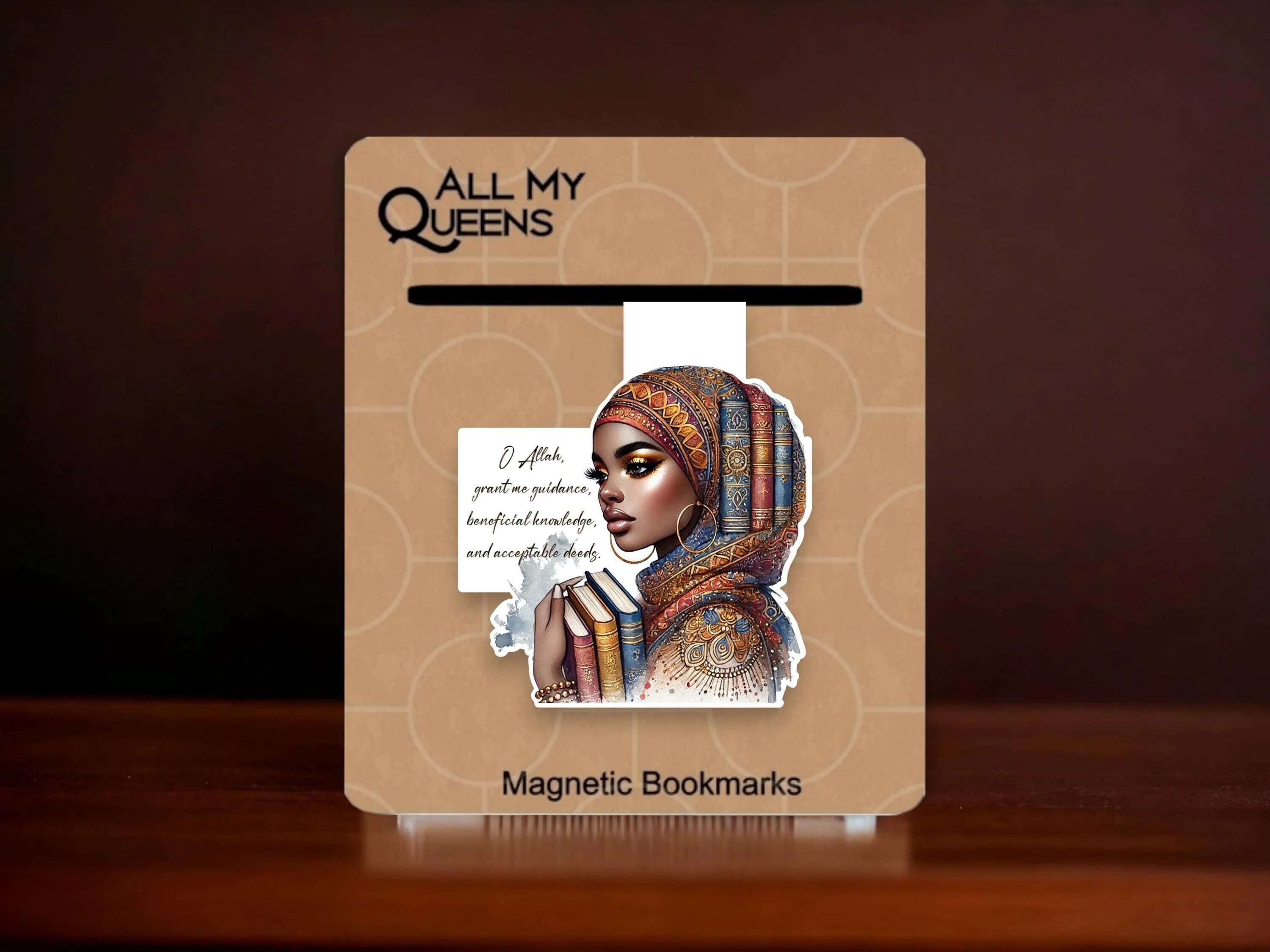 May include: A magnetic bookmark featuring a woman wearing a colorful headscarf and holding a stack of books. The bookmark has the text "O Allah, grant me guidance, beneficial knowledge, and acceptable deeds" on it. The bookmark is on a brown background with the text "All My Queens" and "Magnetic Bookmarks".