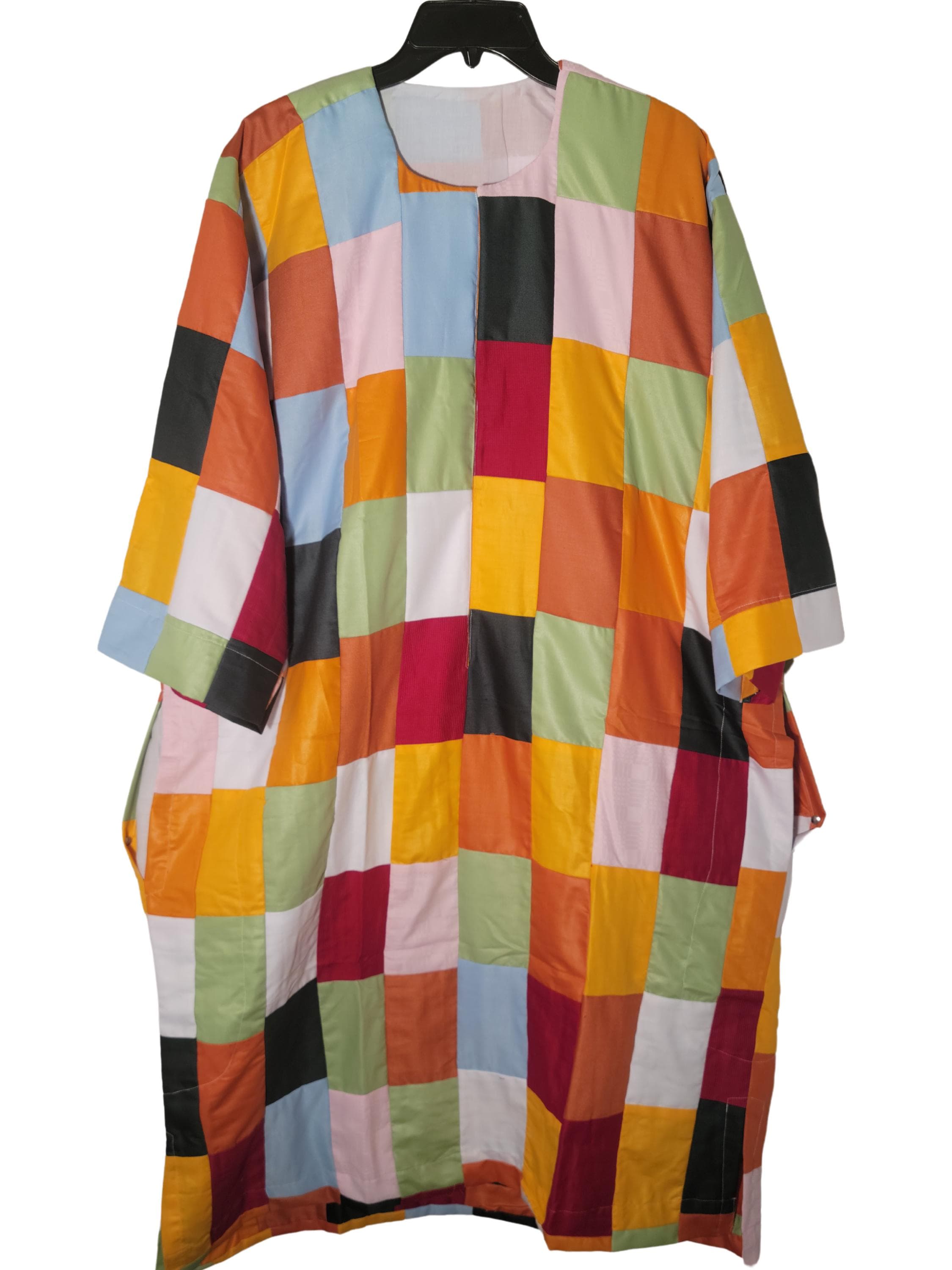 May include: A long-sleeved, patchwork tunic with a round neckline. The tunic is made of various colored fabric squares, including red, orange, yellow, green, blue, black, and white.