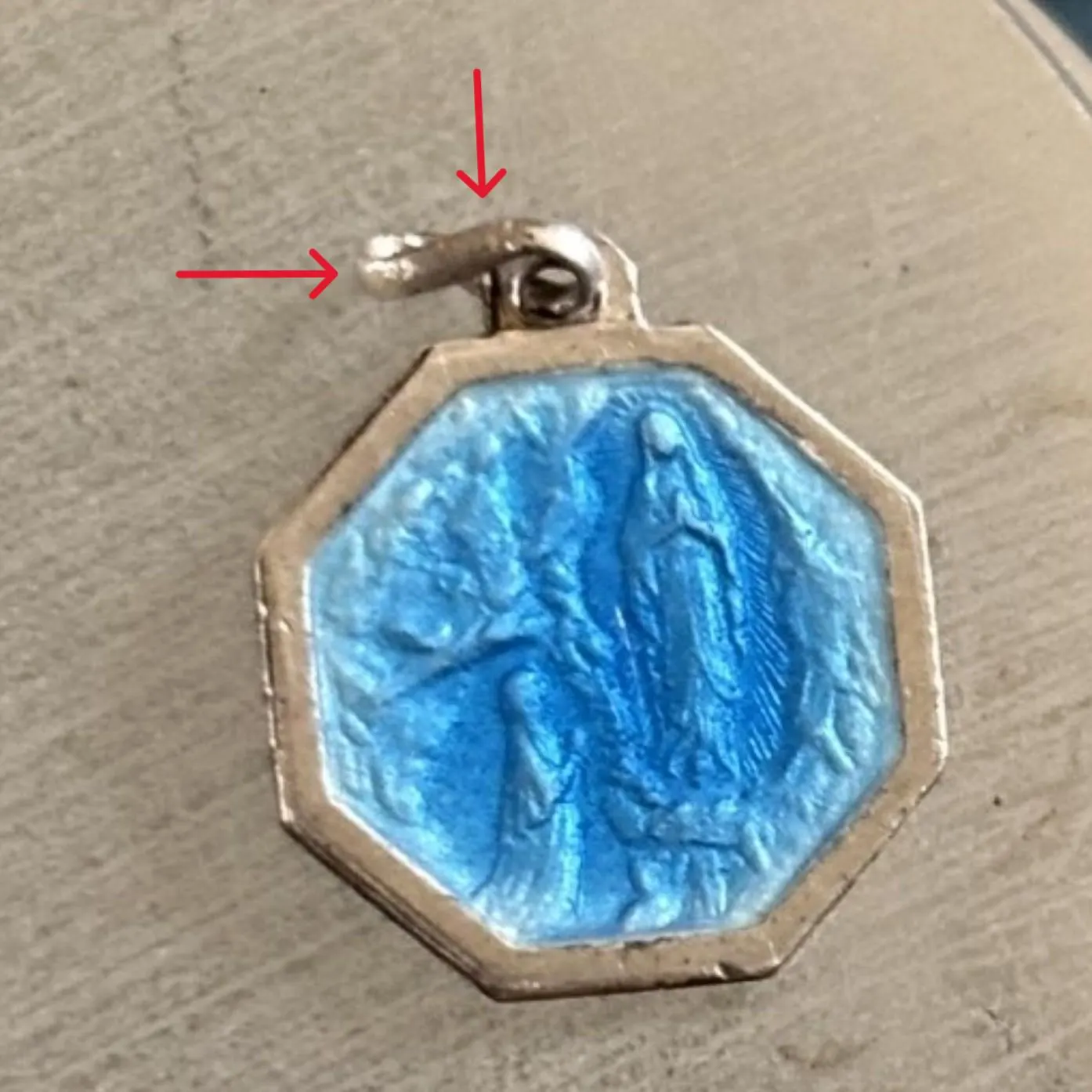 Red arrows showing twist in silver hanging loop on silver & blue enamel octagonal religious charm