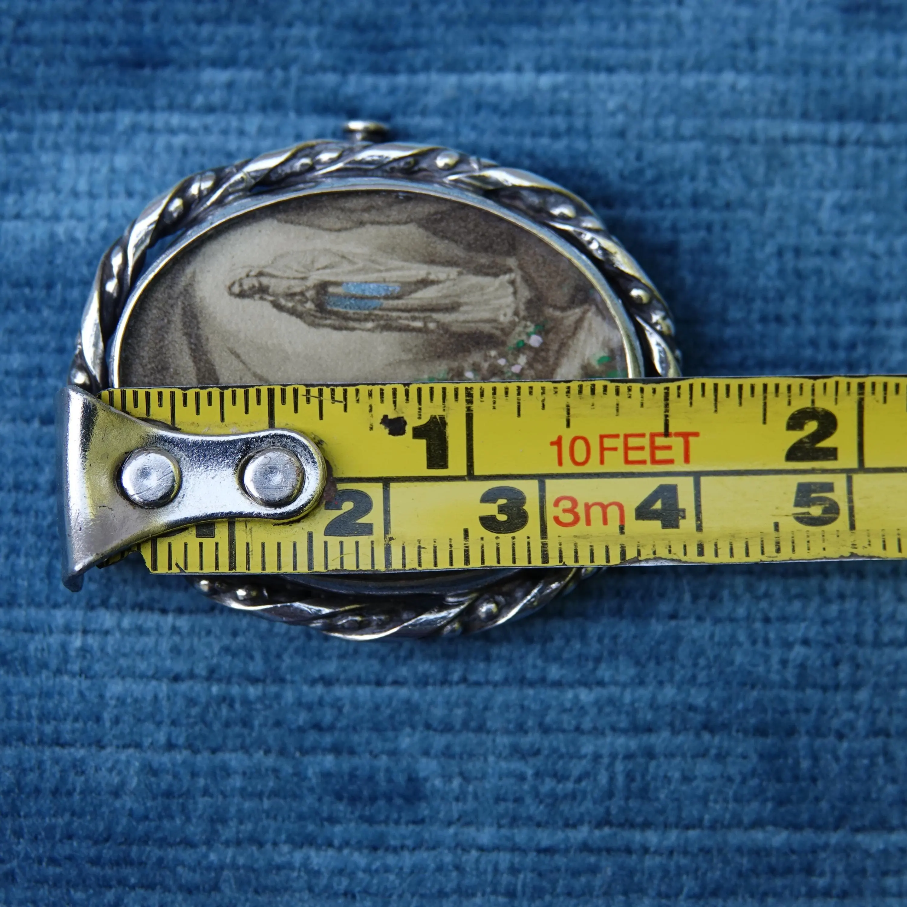 Oval Lourdes sovenir lithograph brooch shown with tape measure