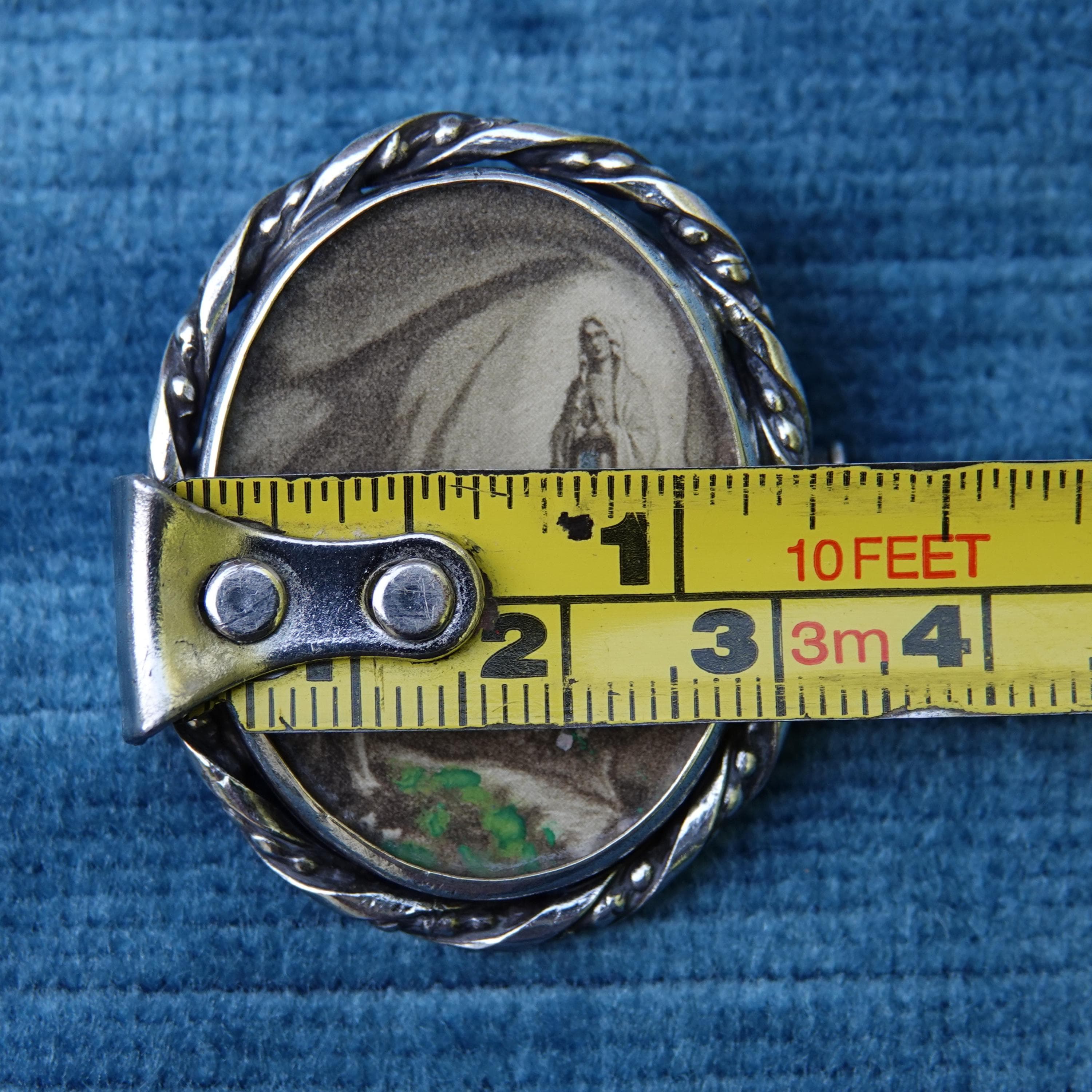 Vintage Lourdes lithograph brooch shown with tape measure