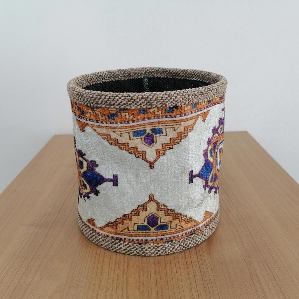A decorative woven basket with a patterned design, placed on a wooden surface.