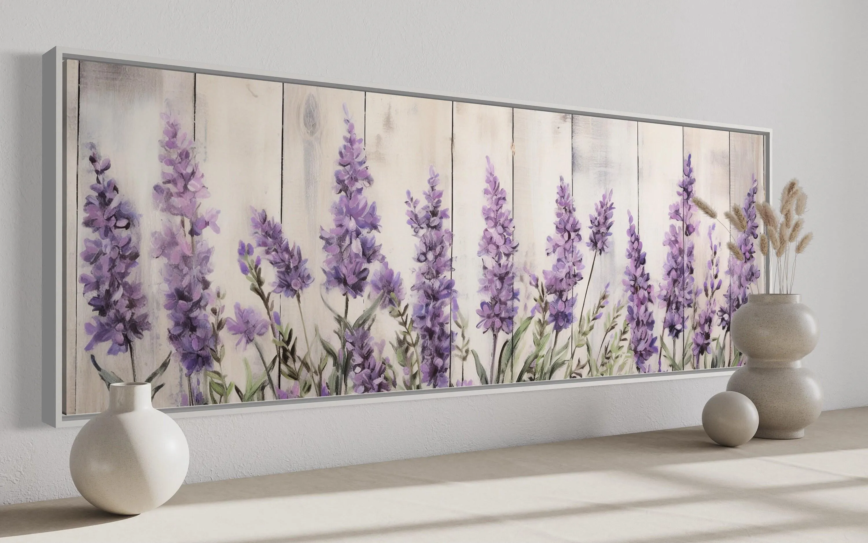 a large framed painting of purple flowers on a wooden background, with two white vases placed on a wooden surface to the right of the painting.