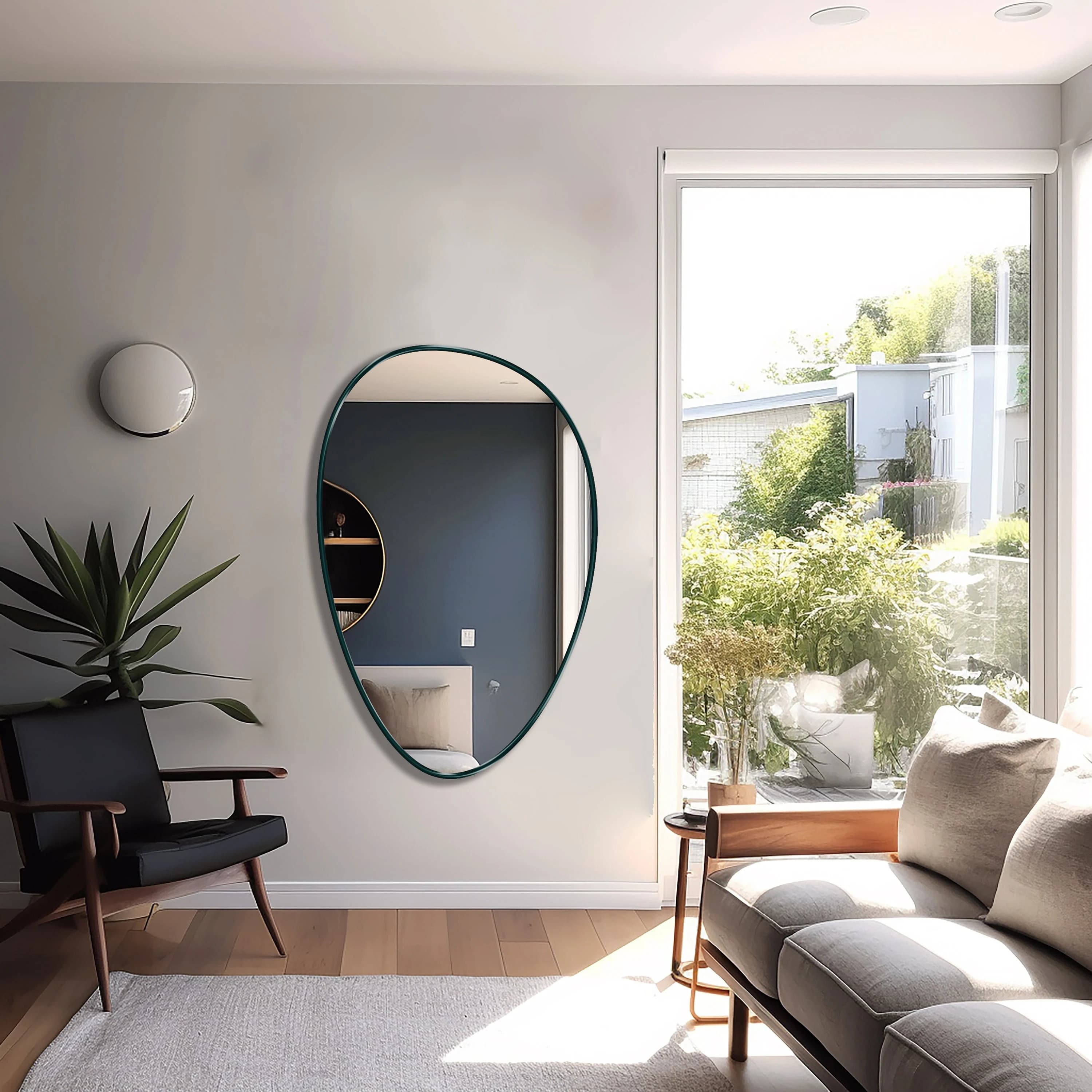 Egg shaped mirror with emerald frame hung on the wall of a living room.