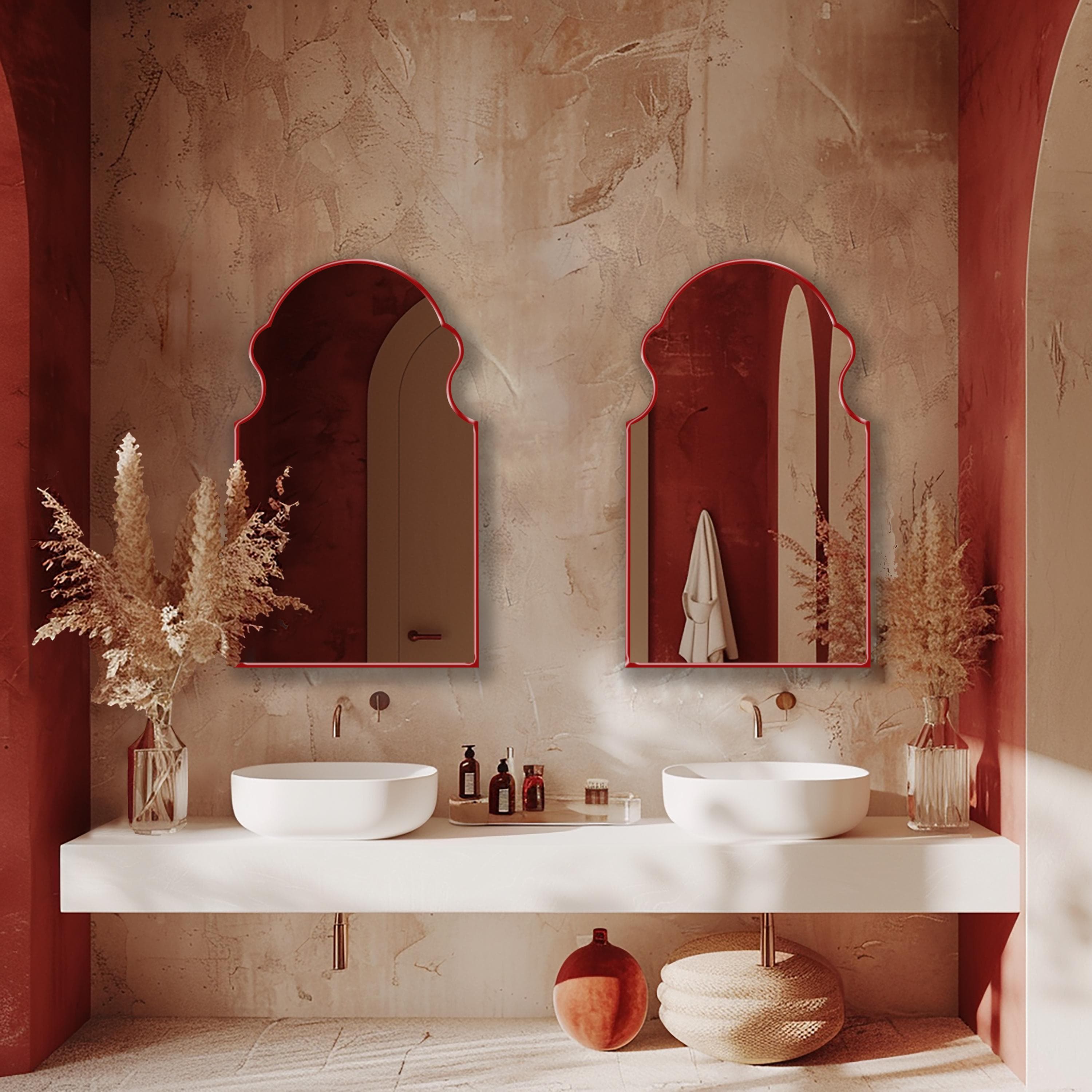 Two Bohemian Mirrors with red frame finish hung on the wall of a bathroom over two bathroom sinks.