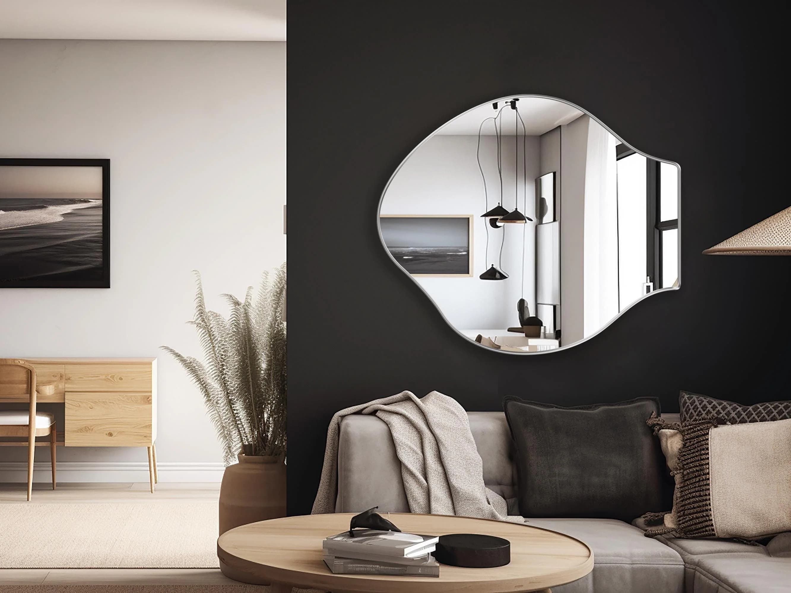 Pisces mirror with silver frame finish hung on the wall of a living room over a couch.