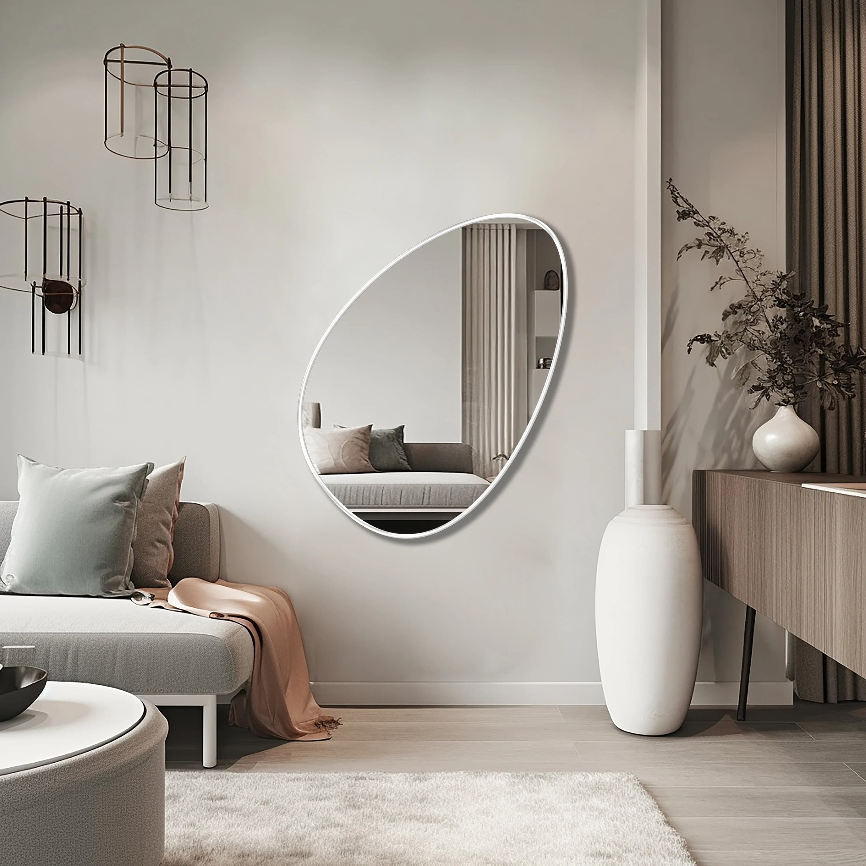 Egg shaped mirror with white frame hung on the wall of a living room.