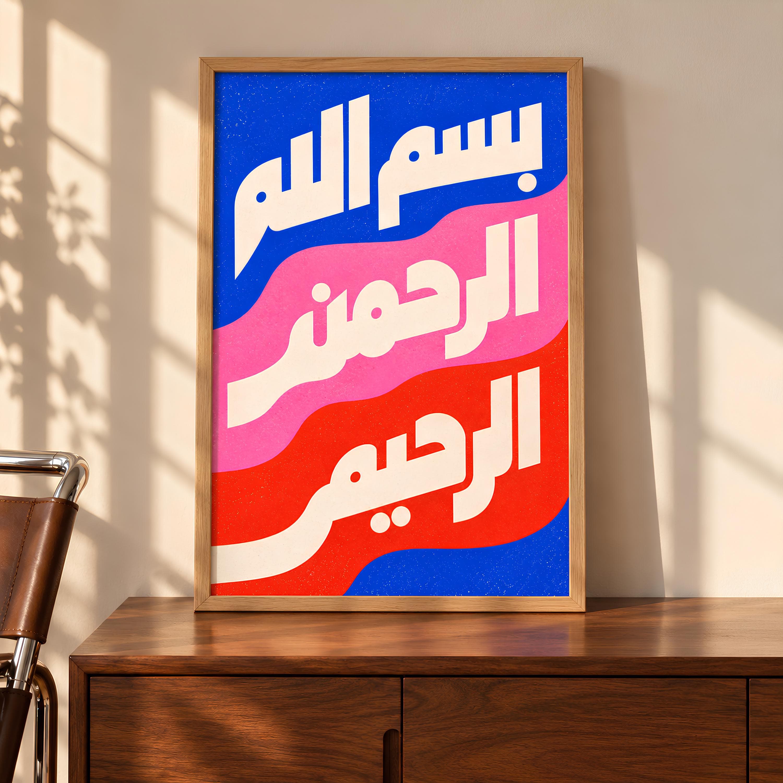 A rectangular framed wall art piece featuring white Arabic calligraphy against a background of wavy horizontal stripes in blue, pink, and red. The text reads Bismillah ar-Rahman ar-Rahim, presented in a bold, modern, and clean typeface.