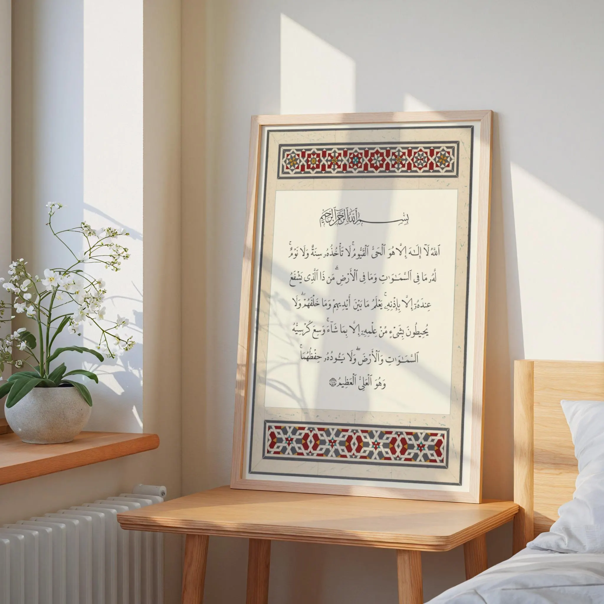 A framed wall art print featuring Arabic calligraphy of the Ayat al-Kursi. The text is centered on a cream background, framed by decorative geometric borders in red, black, and gold patterns. The print is displayed in a light wood frame.