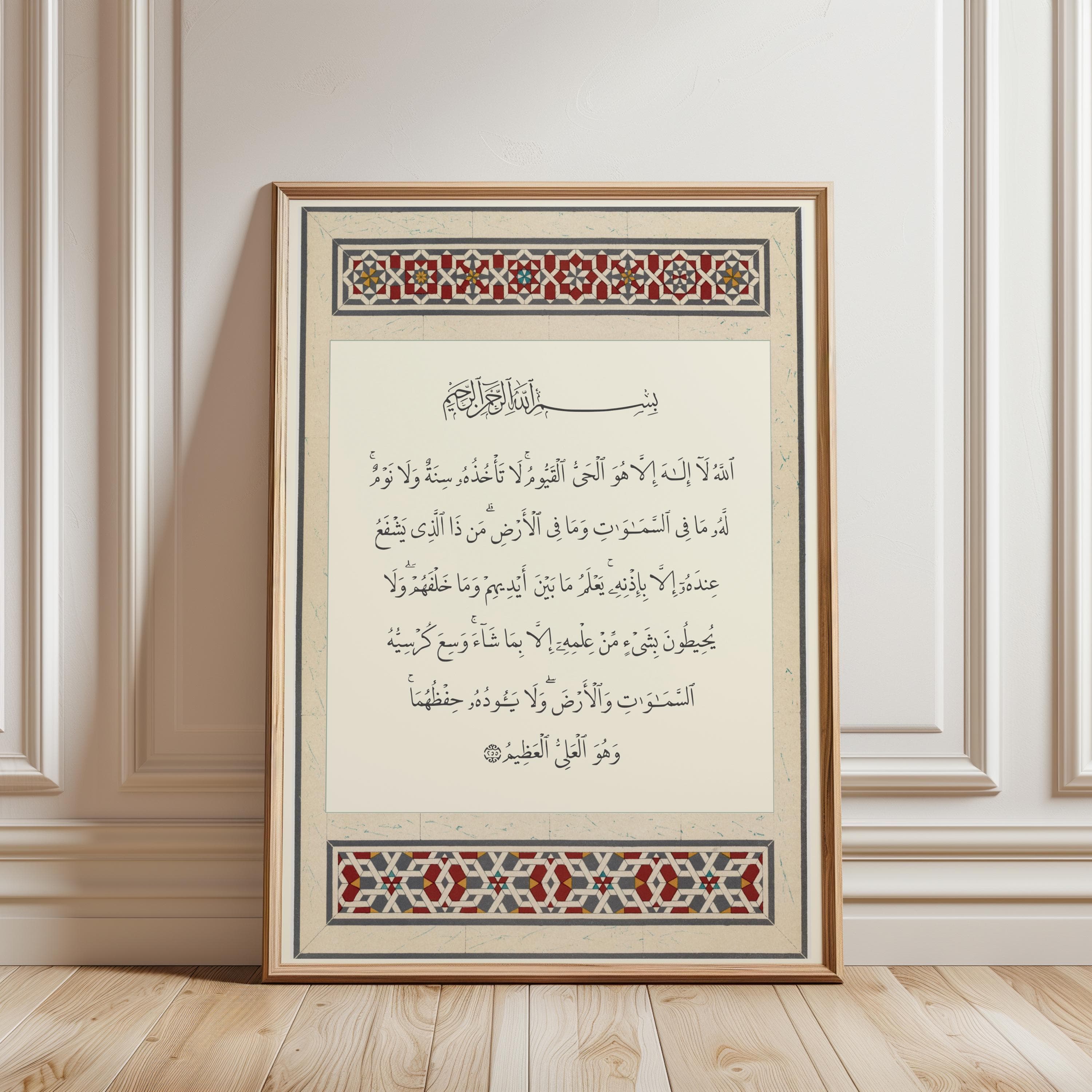 A rectangular framed wall art piece featuring black Arabic calligraphy of Ayatul Kursi on a cream background. The design includes decorative borders at the top and bottom with intricate geometric patterns in red, blue, and gold tones.
