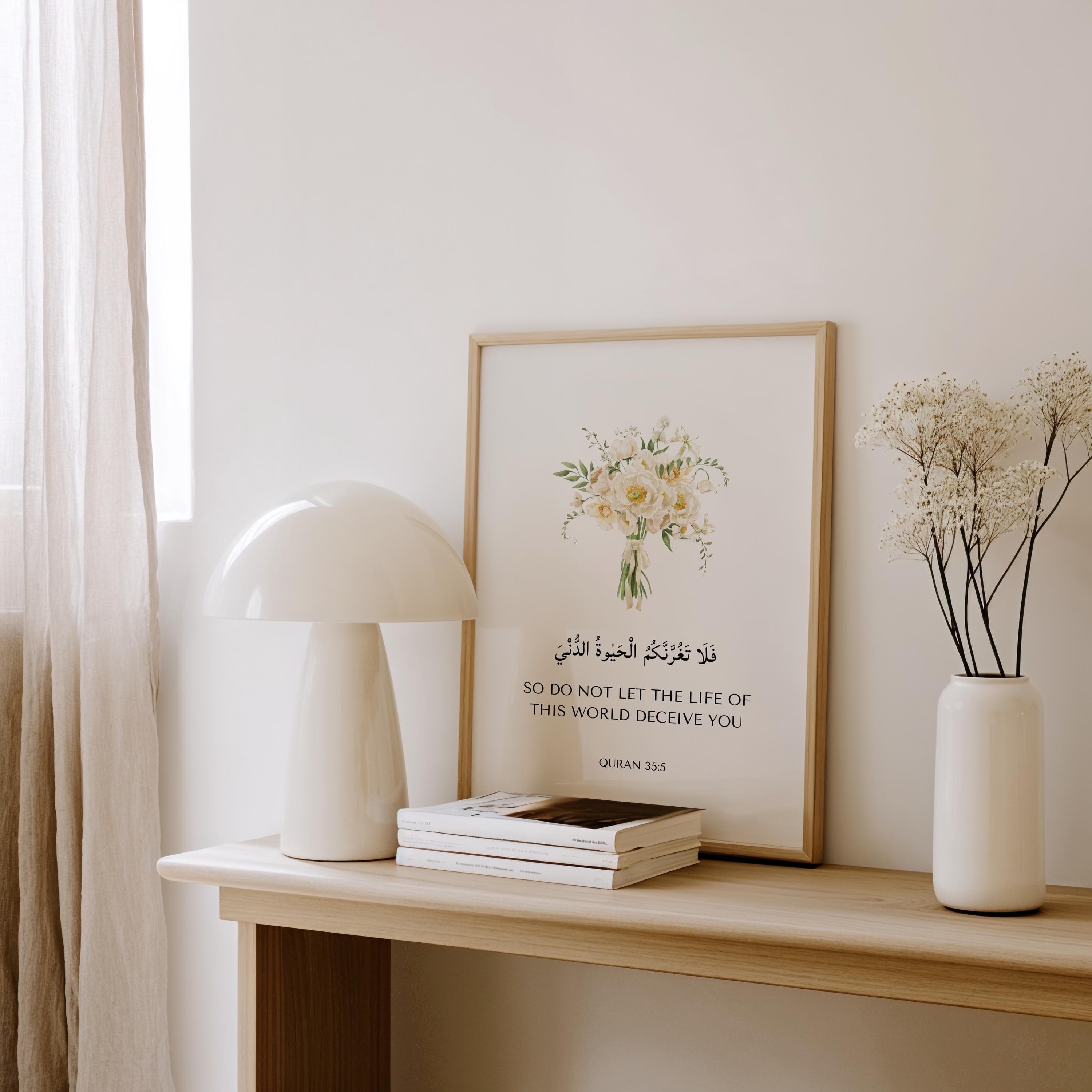 Framed islamic wall art piece featuring Quran Quote 35:5 with white flower bouquet. Set on a wooden floor. An ideal islamic art quran verse prints for islamic home decor, islamic wall decor, nursery art, or as ramadan eid gifts for muslims