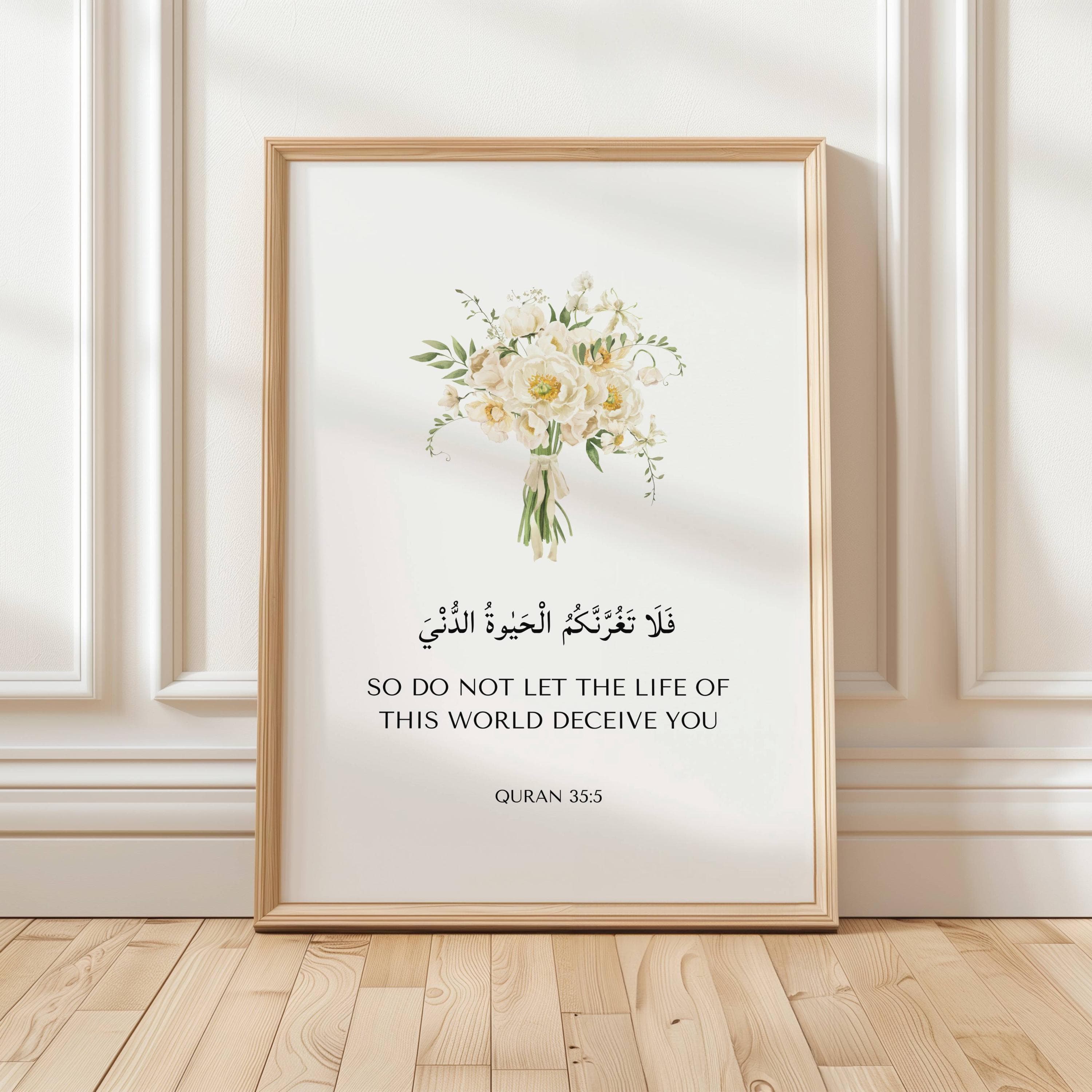 Framed islamic wall art piece featuring Quran Quote 35:5 with white flower bouquet. Set on a wooden floor. An ideal islamic art quran verse prints for islamic home decor, islamic wall decor, nursery art, or as ramadan eid gifts for muslims
